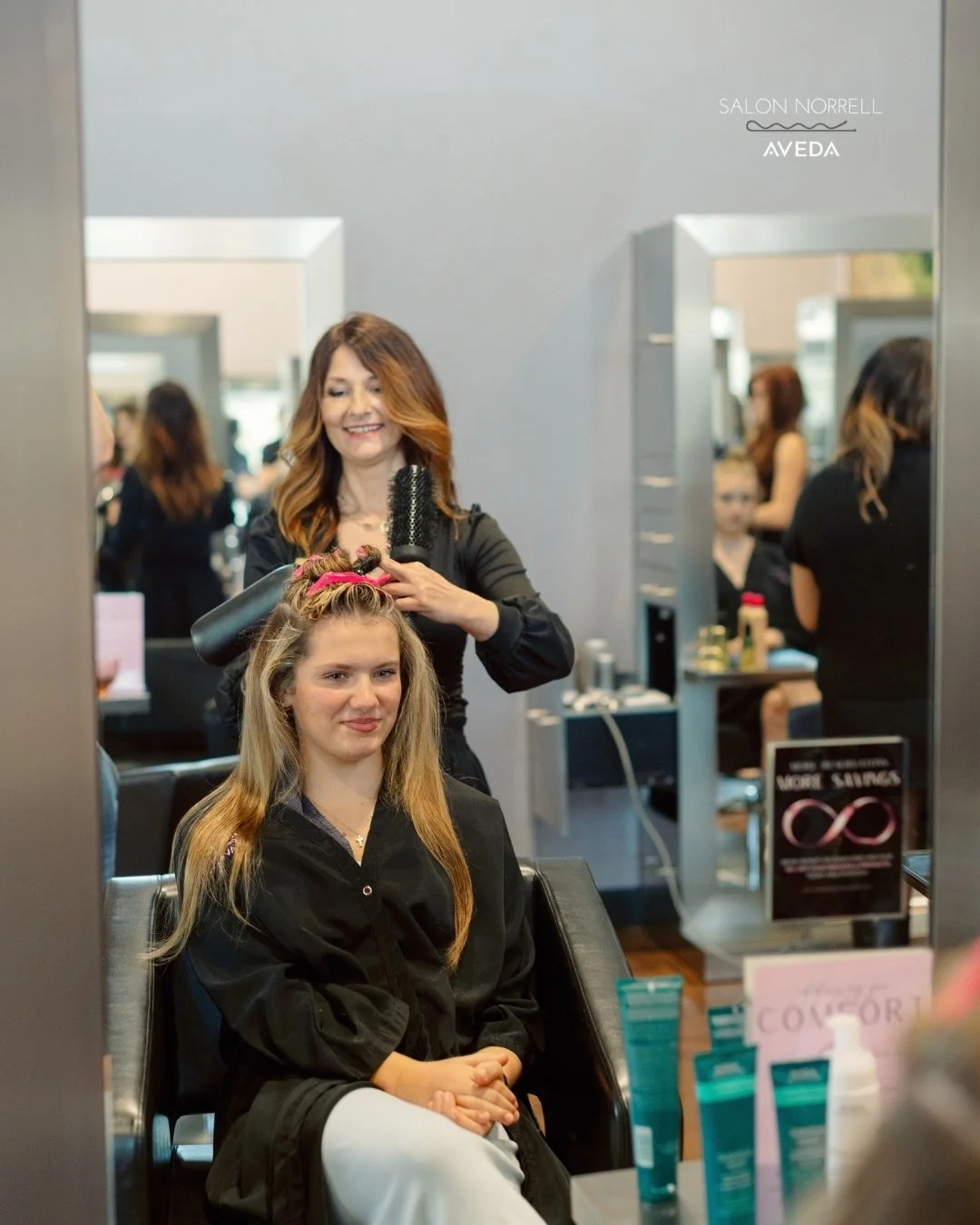 Nina — dimensional brunette, balayage, and lived-in color specialist at Salon Norrell AVEDA in Carrollwood Tampa doing a bouncy blowout