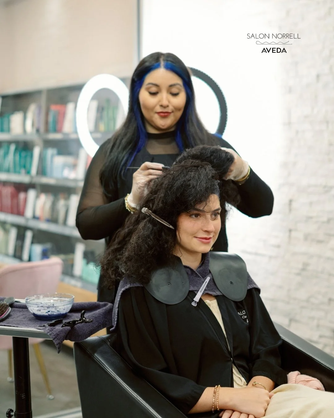 Marcela — vivid color, curly hair, and dimensional haircolor specialist at Salon Norrell AVEDA in Hyde Park Tampa doing a color retouch service on model