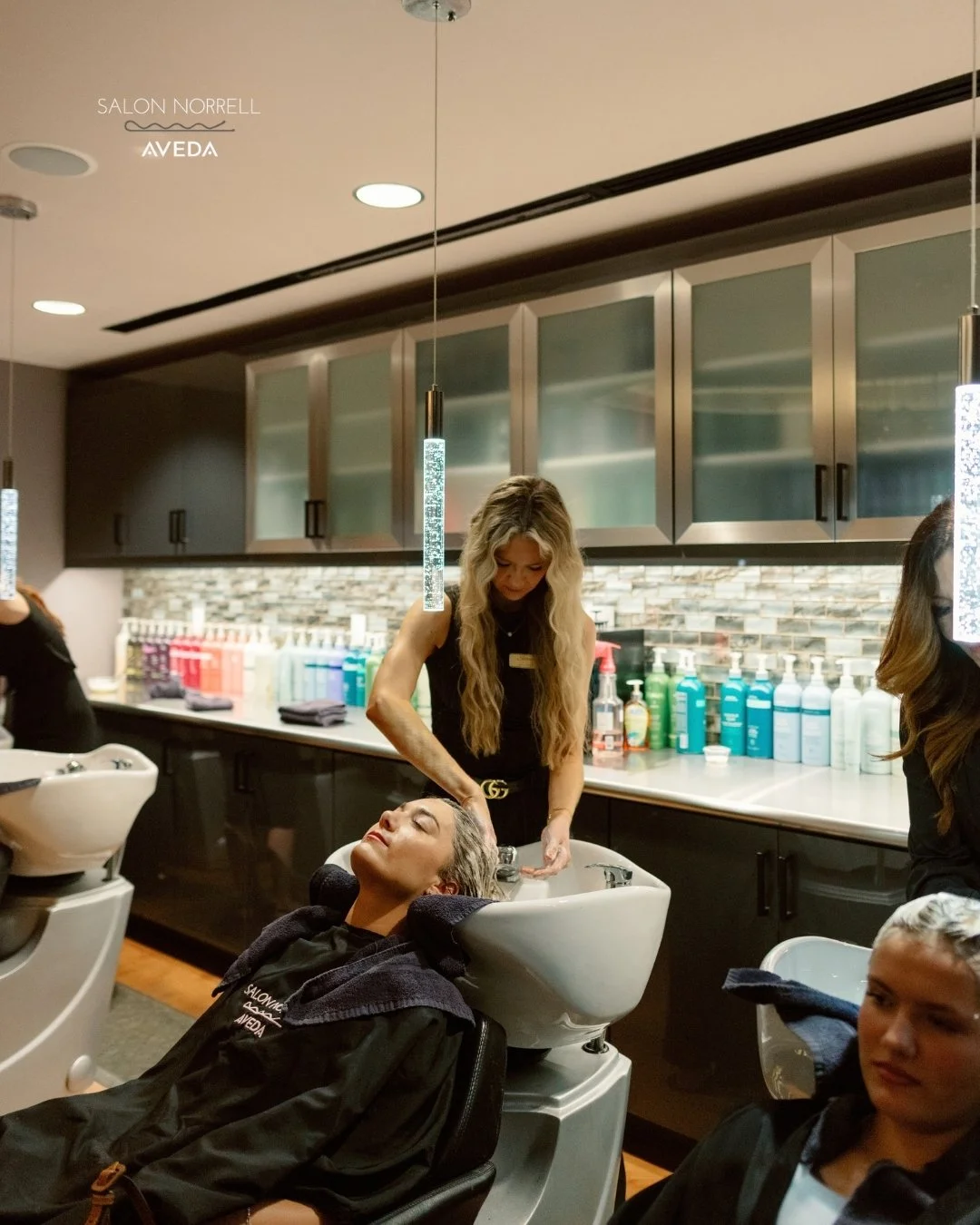 Shannon — transformational blonding and Bellami, VoMor, and Butterfly extension specialist at Salon Norrell AVEDA in Carrollwood Tampa doing a scalp massage ritual on model