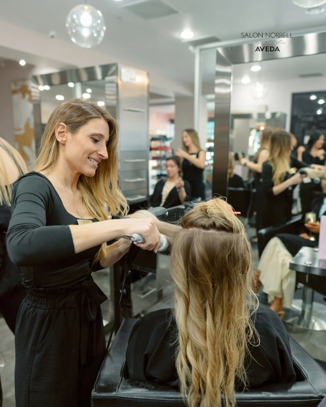 Anna — grey blending, corrective color, and curly hair specialist at Salon Norrell AVEDA in Hyde Park Tampa doing a bouncy blowout with beach wave curls