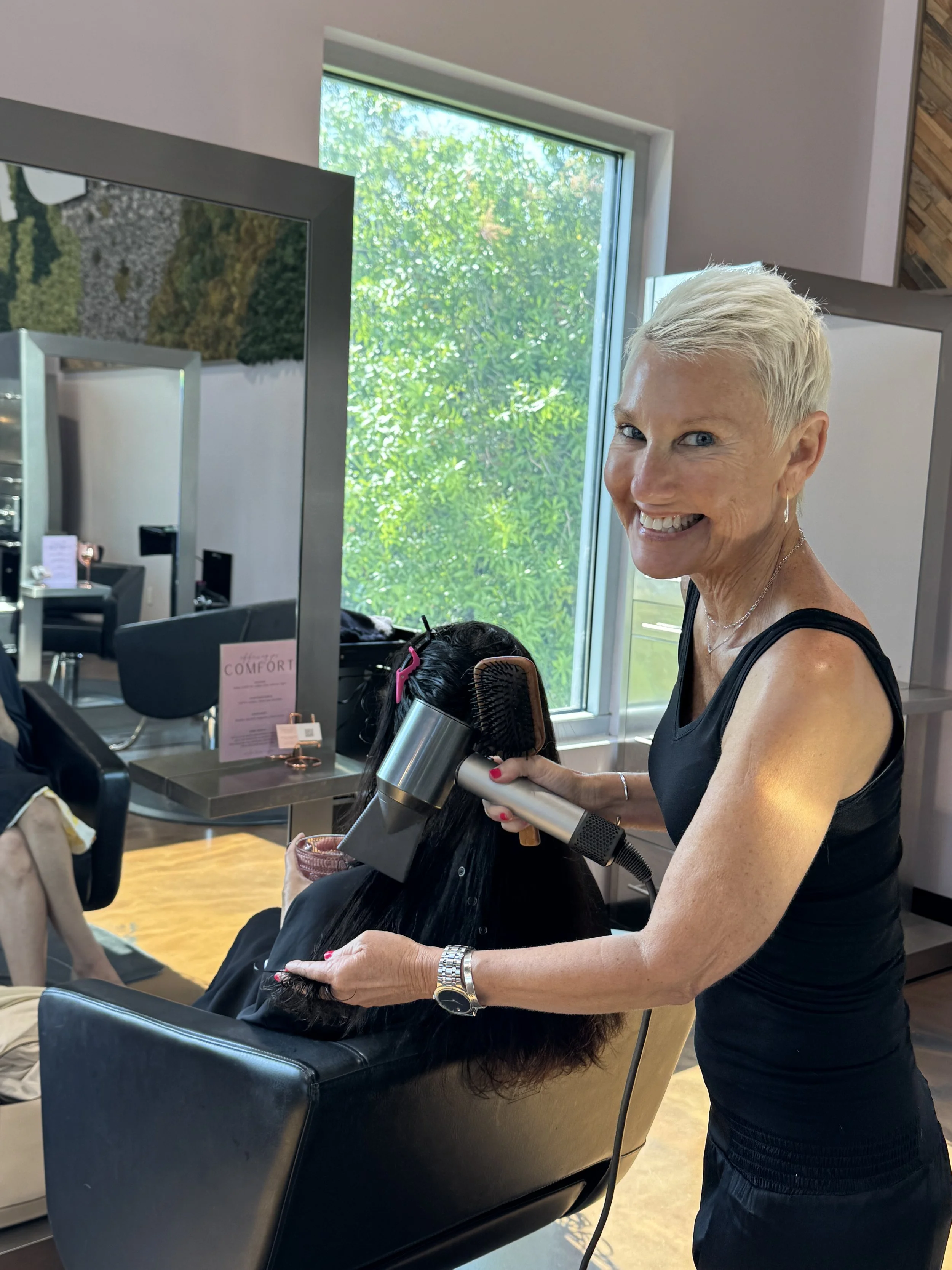 Lori — dimensional color, men's haircuts, pixies, and precision haircut specialist at Salon Norrell AVEDA in Carrollwood Tampa doing bouncy blowout on model