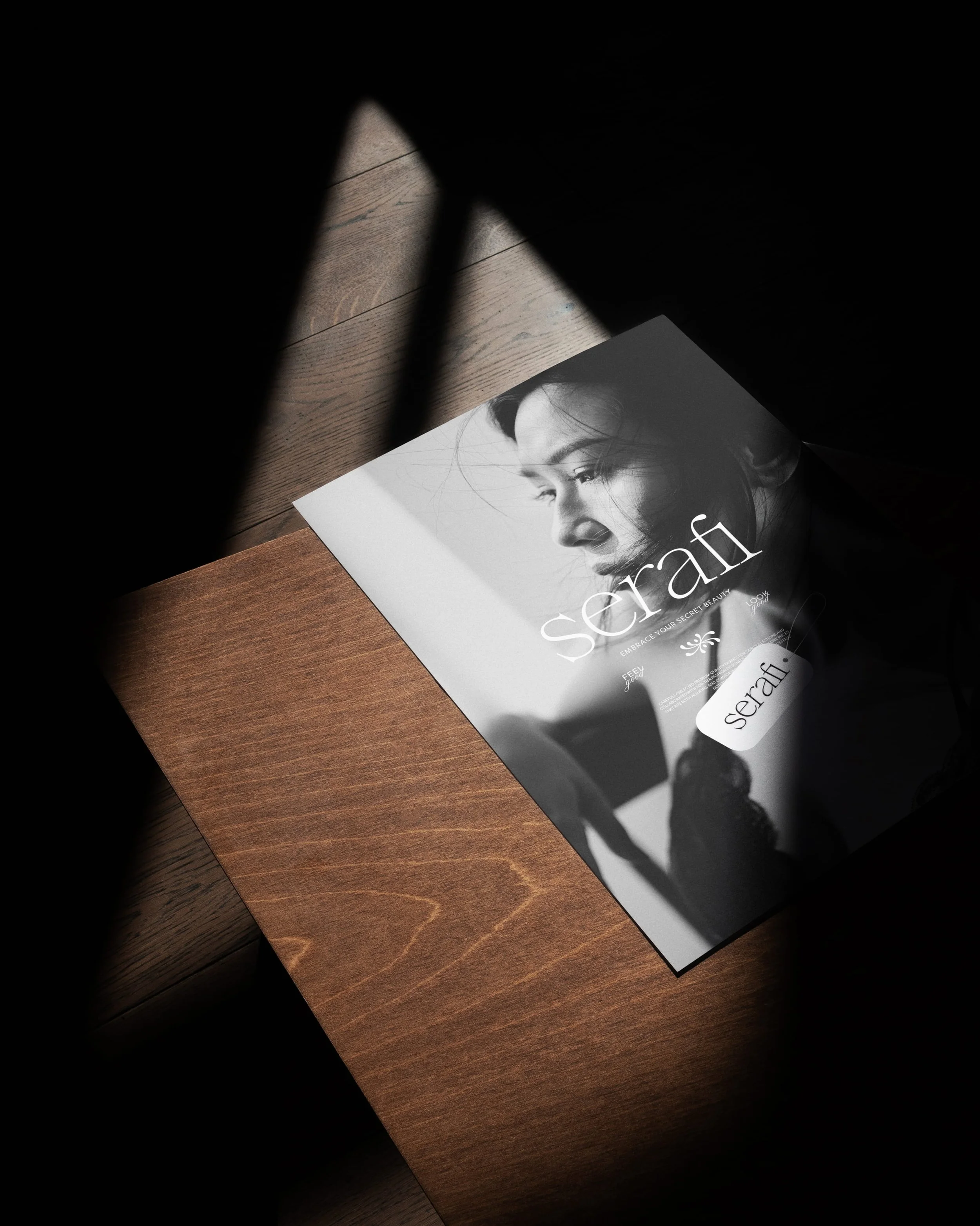 A magazine titled 'Serafi' with a black-and-white profile of a woman with dark hair on the cover, placed on a wooden surface, partially shadowed.