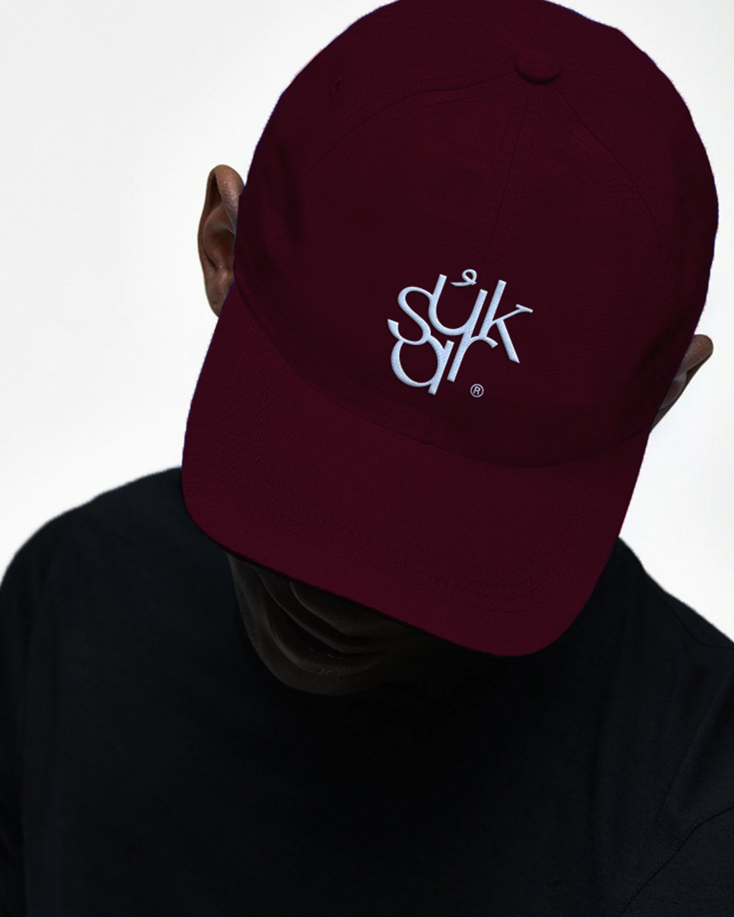 Person wearing a burgundy baseball cap with white embroidered logo, viewed from behind, against a plain light background.