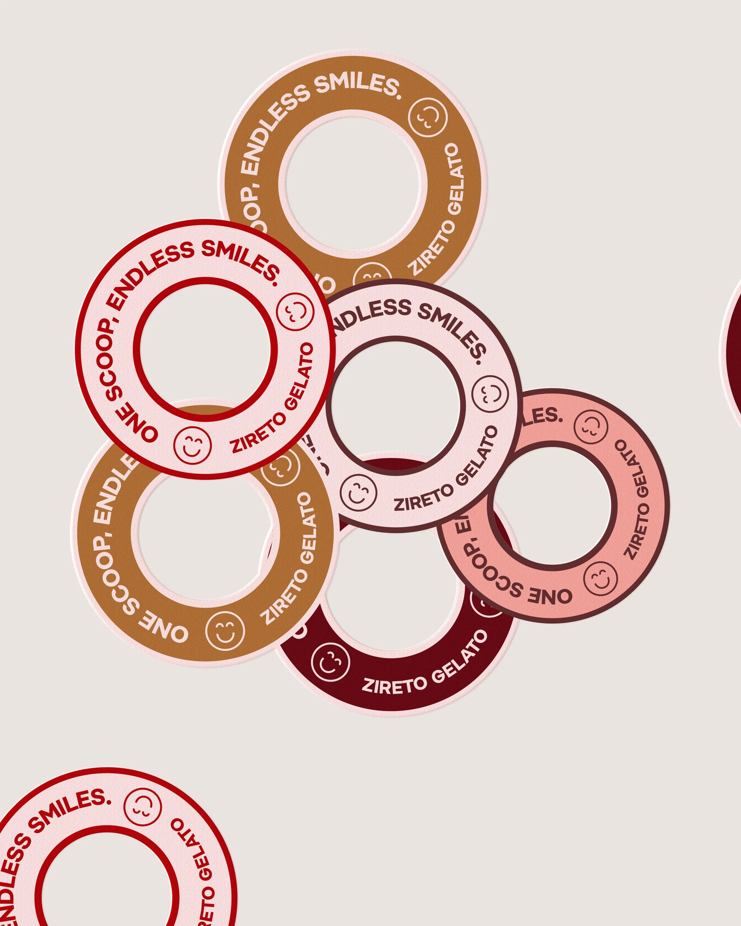 Multiple colorful donut-shaped objects with the text 'One Scoop, Endless Smiles' and 'Zireto Gelato', each with a smiling face icon, overlapping on a light gray background.
