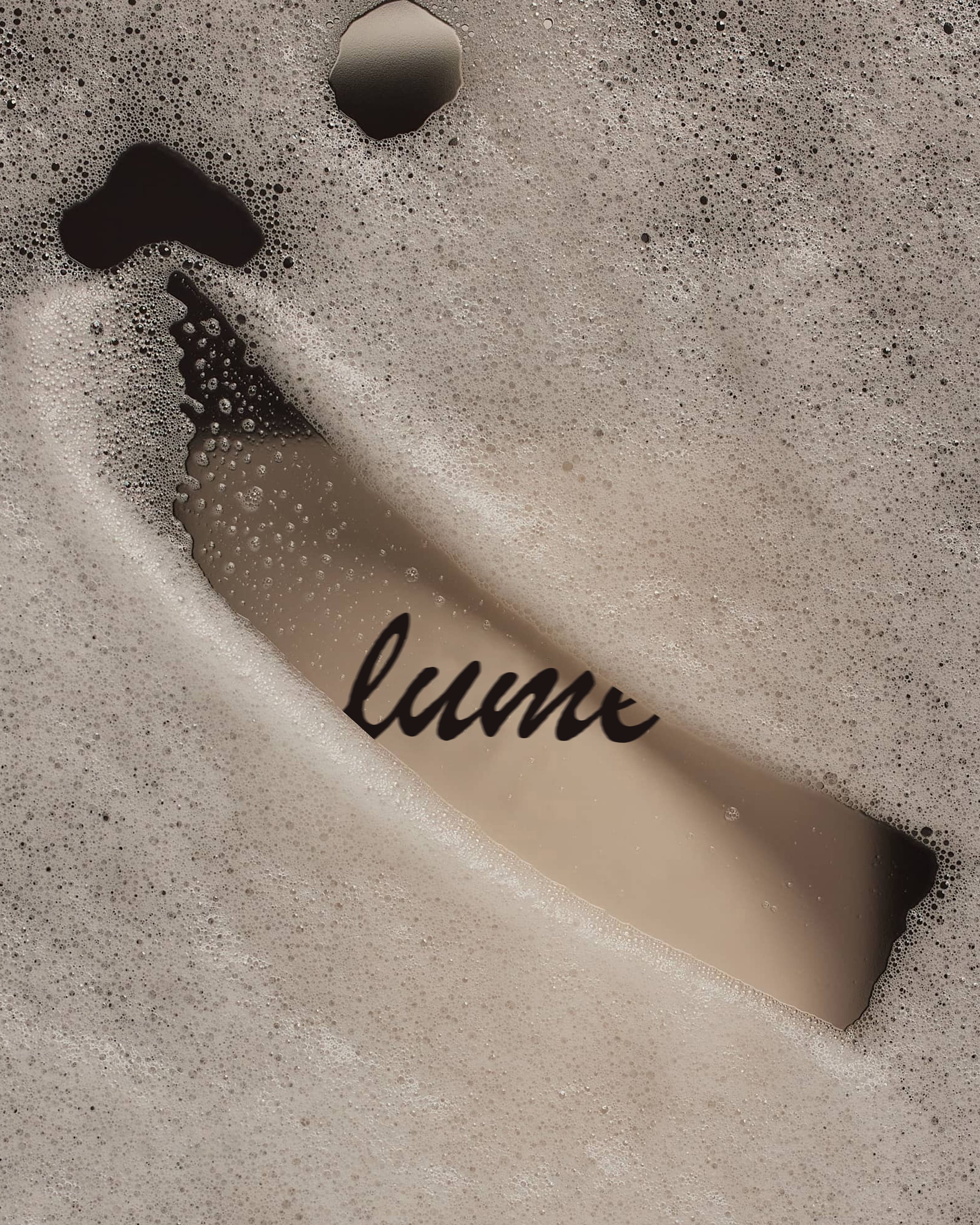 Close-up of foam and bubbles in a beverage, with part of the word 'luxe' visible on the surface.