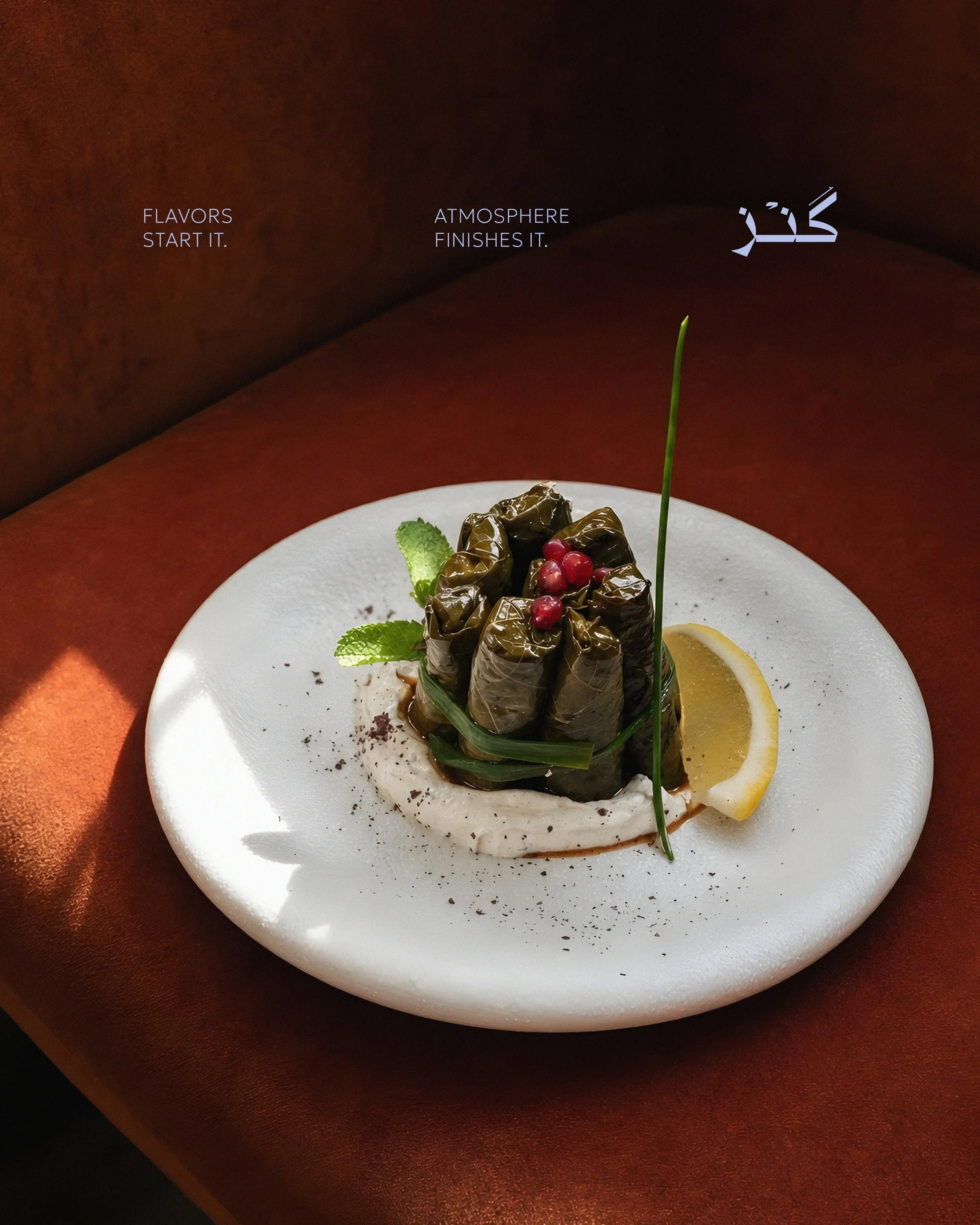 Plate of stuffed grape leaves garnished with red berries, lemon slice, mint leaves, and a green herb, on a white plate.