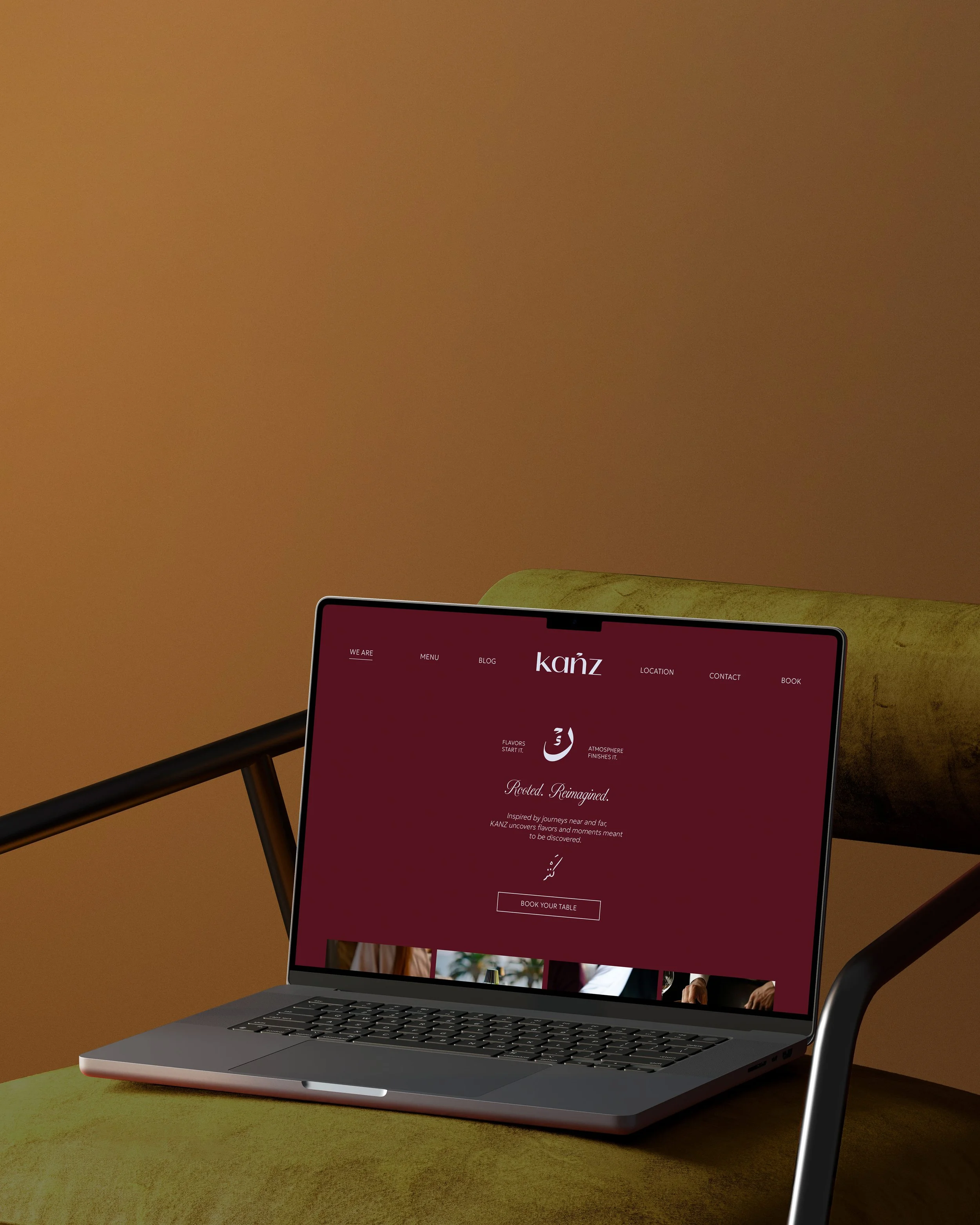 A laptop on a green table displaying a website with a maroon background, white text, and images. The website features the logo 'kanz' and menu options like 'We Are,' 'Menu,' 'Blog,' 'Location,' 'Contact,' and 'Book.'