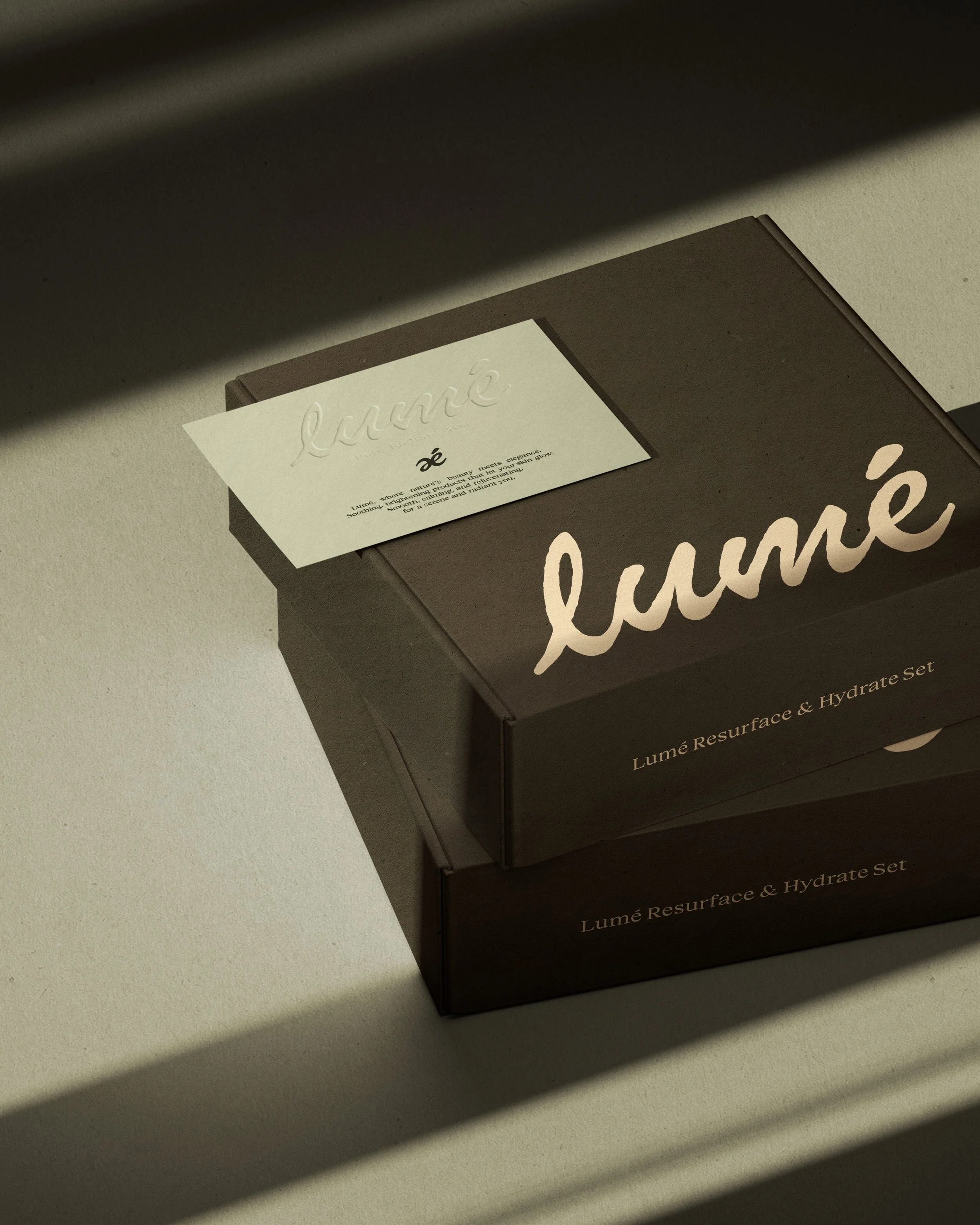 A cardboard box labeled 'Lumé' with a shadow cast over it, placed on a beige surface.