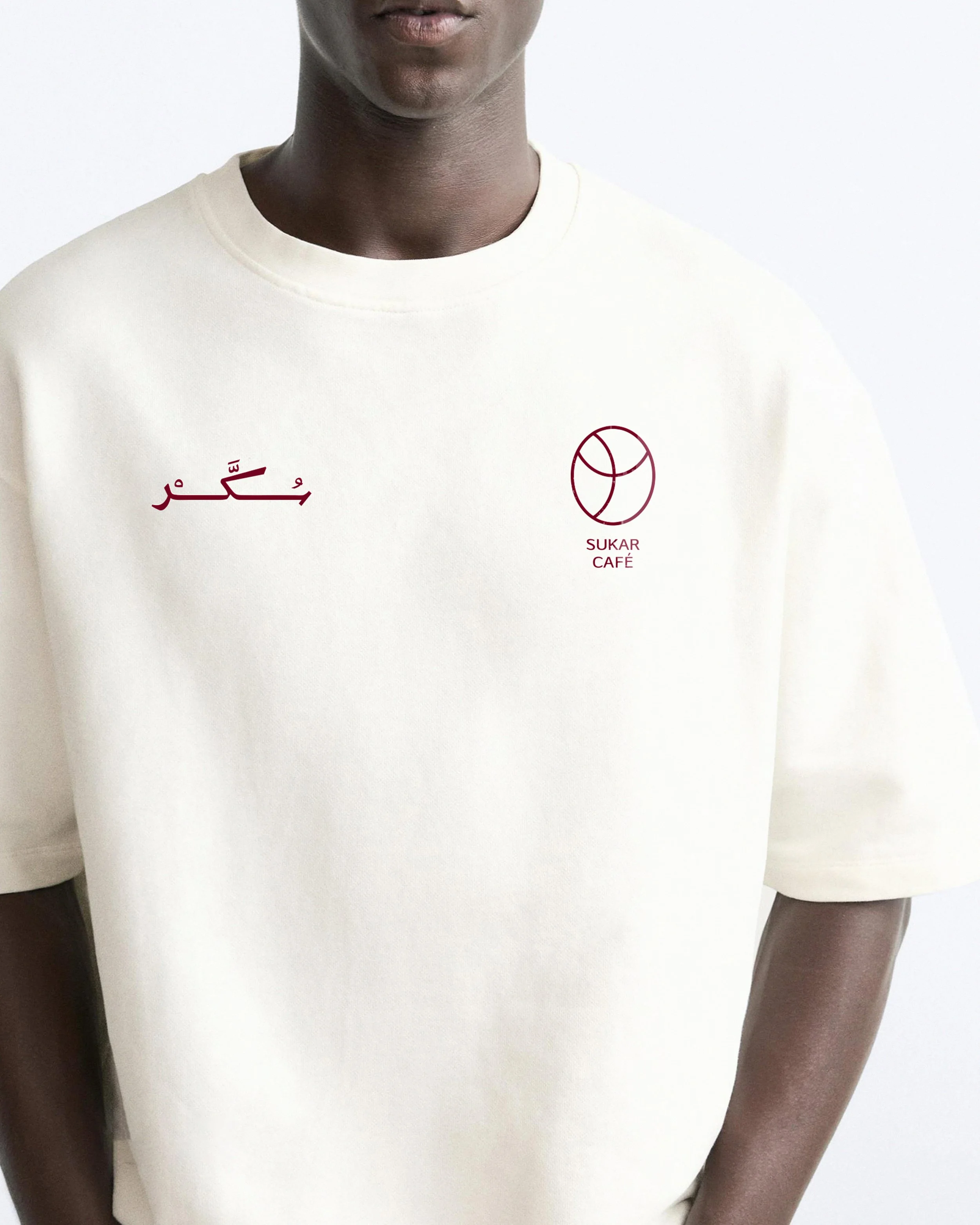 Close-up of a person wearing a white sweatshirt with red and black logos and text, only the lower half of their face and arms are visible.