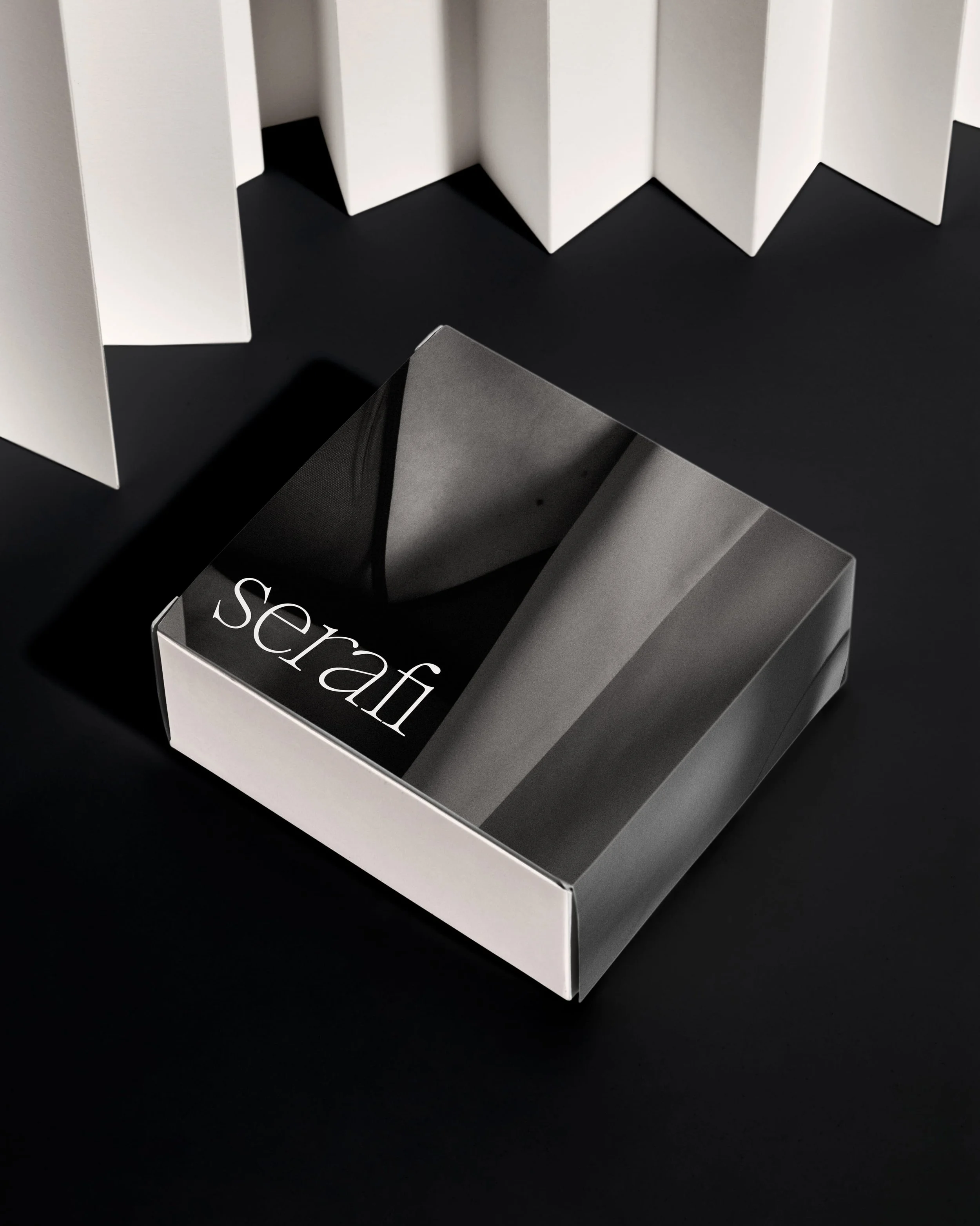 A black and white box labeled "scrap" with angled sides, placed on a black background.