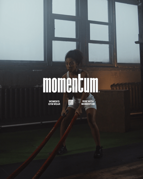 A woman engaging in strength training with battle ropes in a gym, with large windows in the background and the word 'momentum' overlaid.