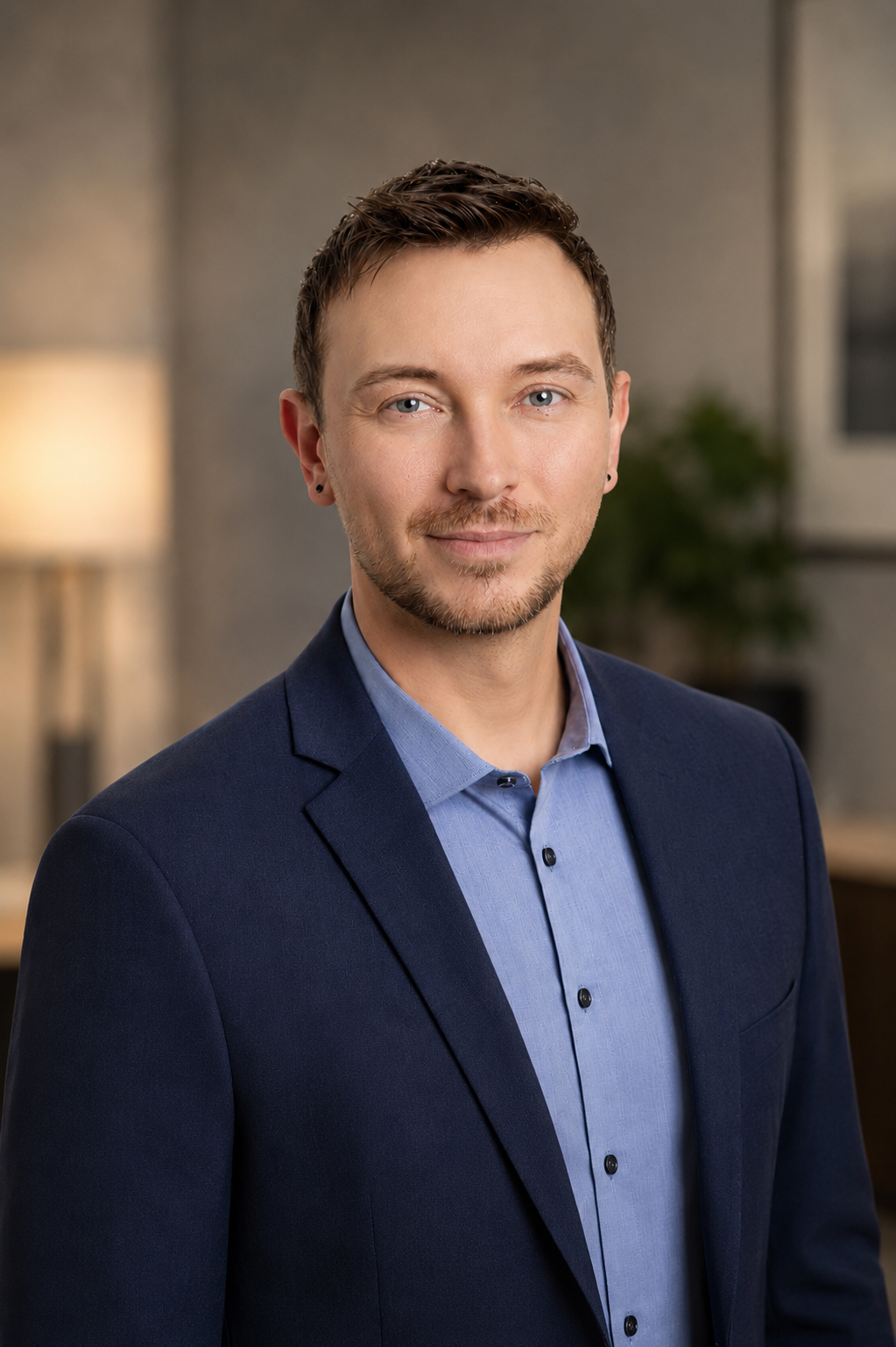 Professional portrait of Maxime Hansen, founder of Hansen Hypnotherapy, wearing a navy blazer and blue shirt.