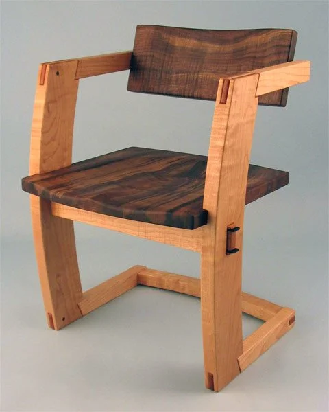 A wooden chair with a dark wood seat and backrest, and light wood frame and arms.