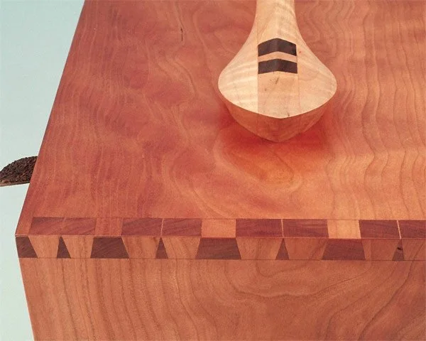 Close-up of a wooden table with a wooden spoon resting on it.