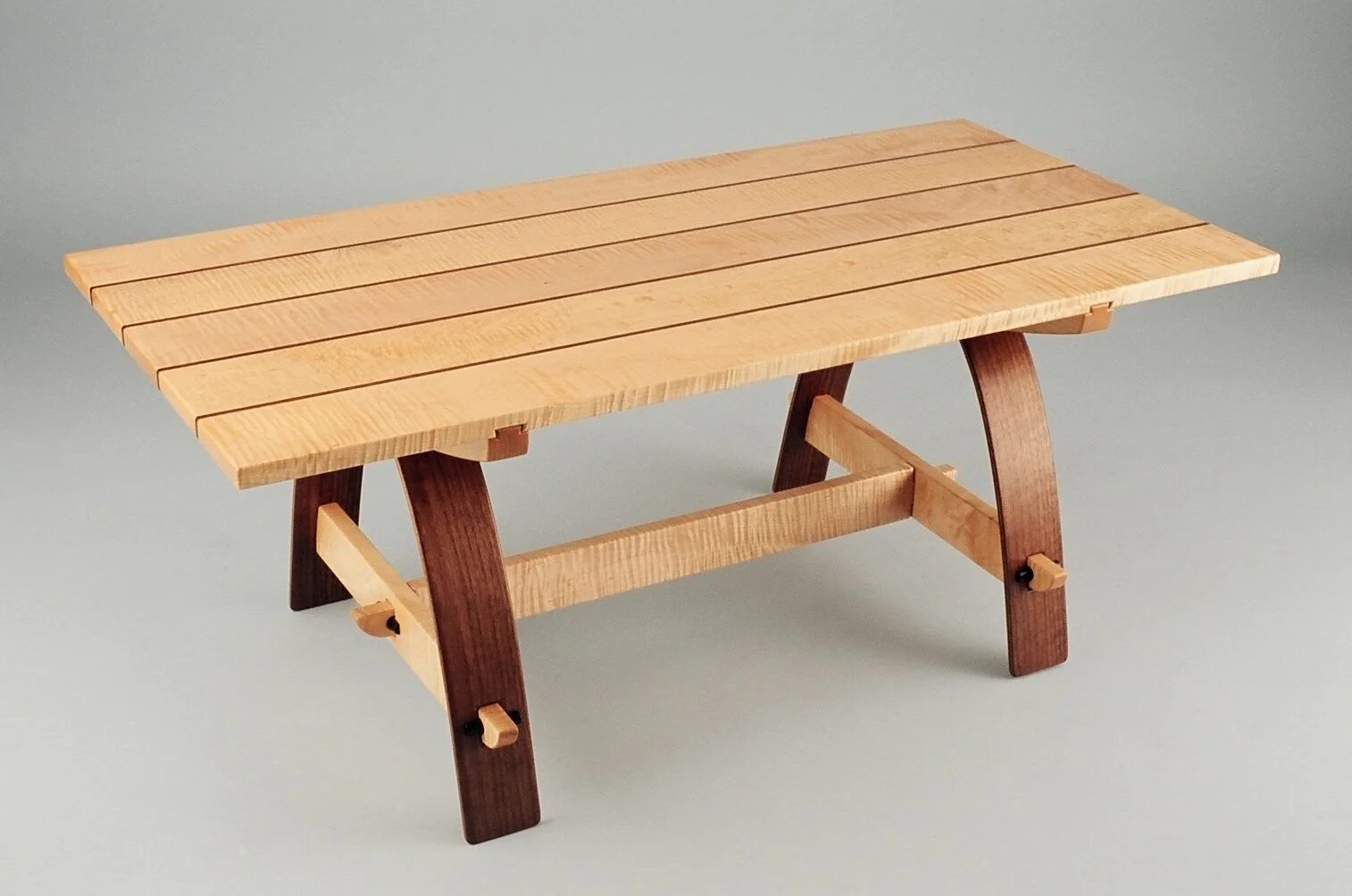 Small wooden table with a light-colored slatted top and darker curved legs.