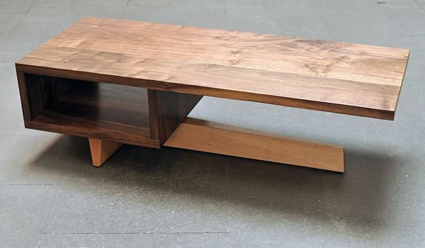 A modern wooden low-profile coffee table with an open cubby and a sliding lower shelf on four angled legs.