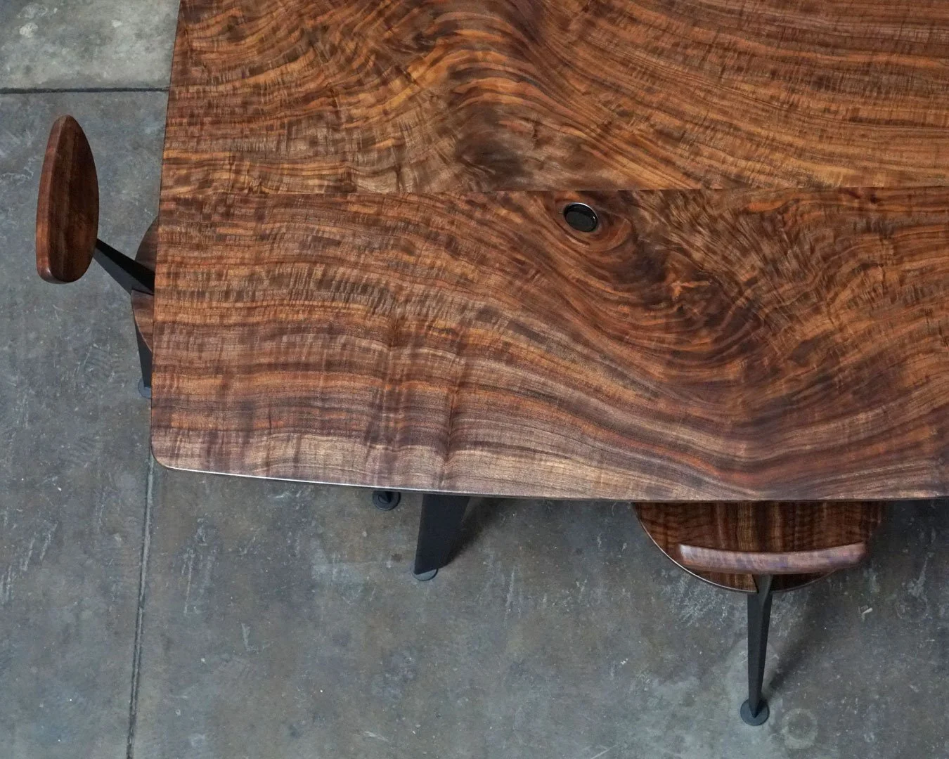 Wooden table with a natural grain pattern and metal legs, seen from above at an angle.