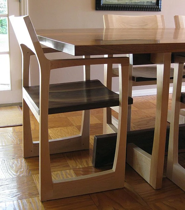 Close-up of a wooden dining chair at a dining table in a room with hardwood flooring.
