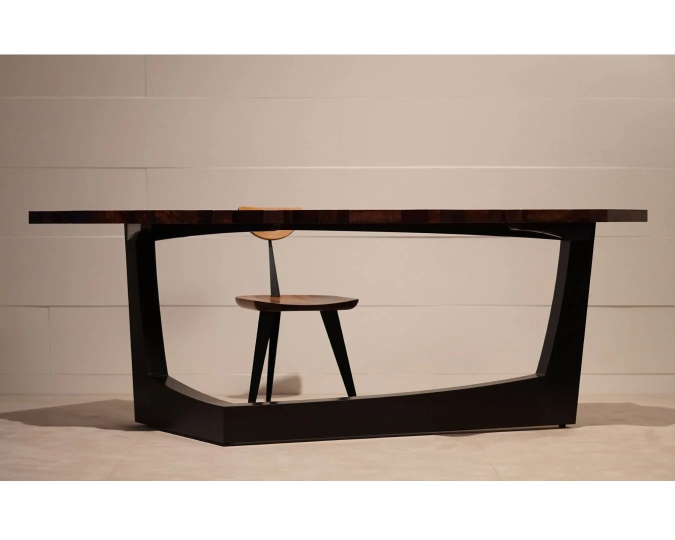 Modern wooden table with a curved black base and a matching wooden chair with black legs, set against a light-colored wall.
