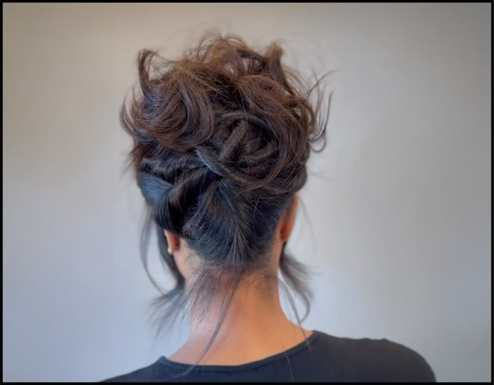 Back view of a woman with curled brown hair styled in an updo.