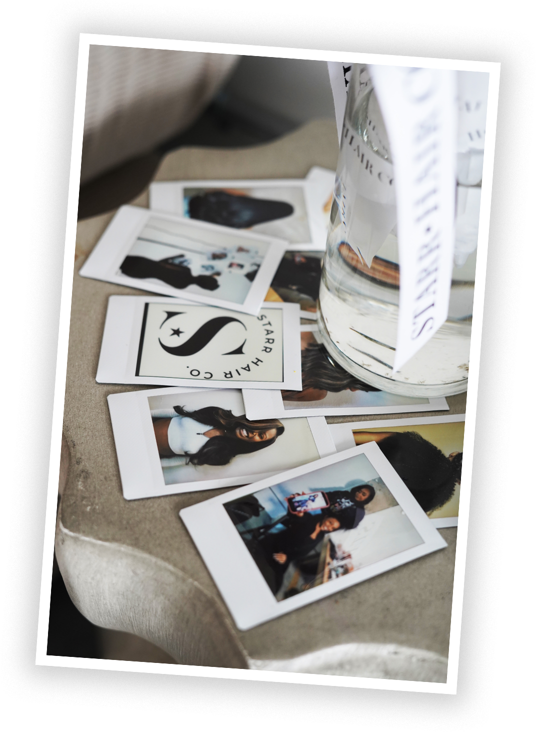 Photographs and a logo on a table, with a glass of water and a bucket nearby.
