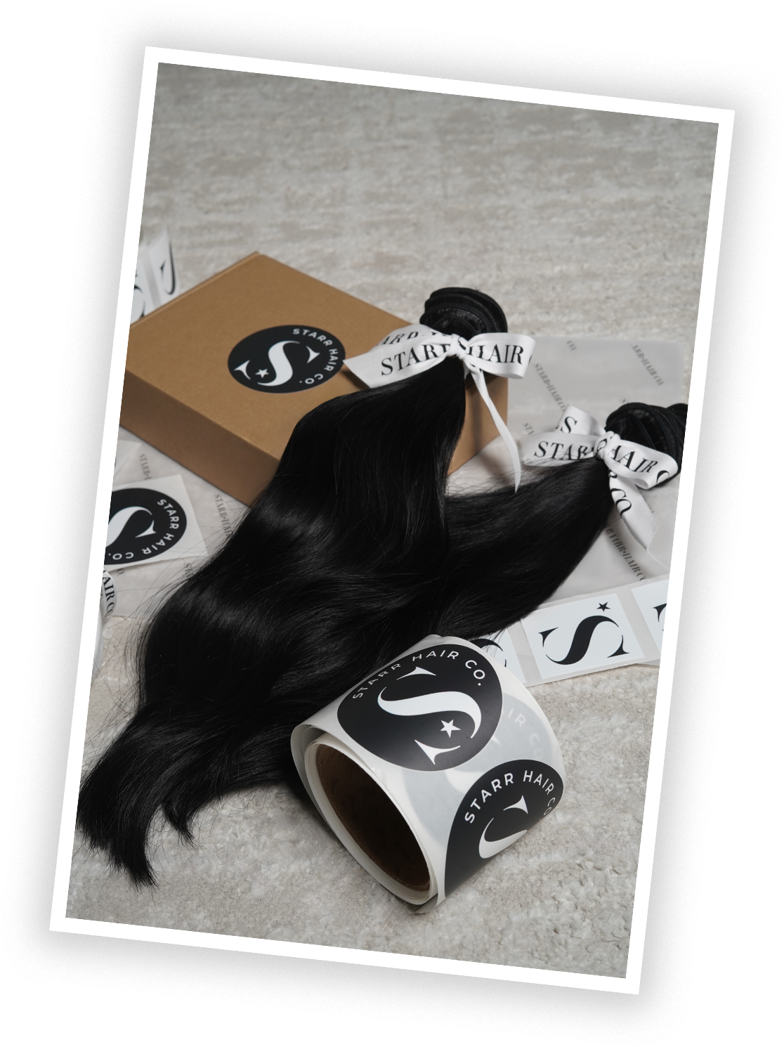 Bundles of black hair extensions with Starrr Hair Co branding, a cardboard box, and packaging materials on a surface.