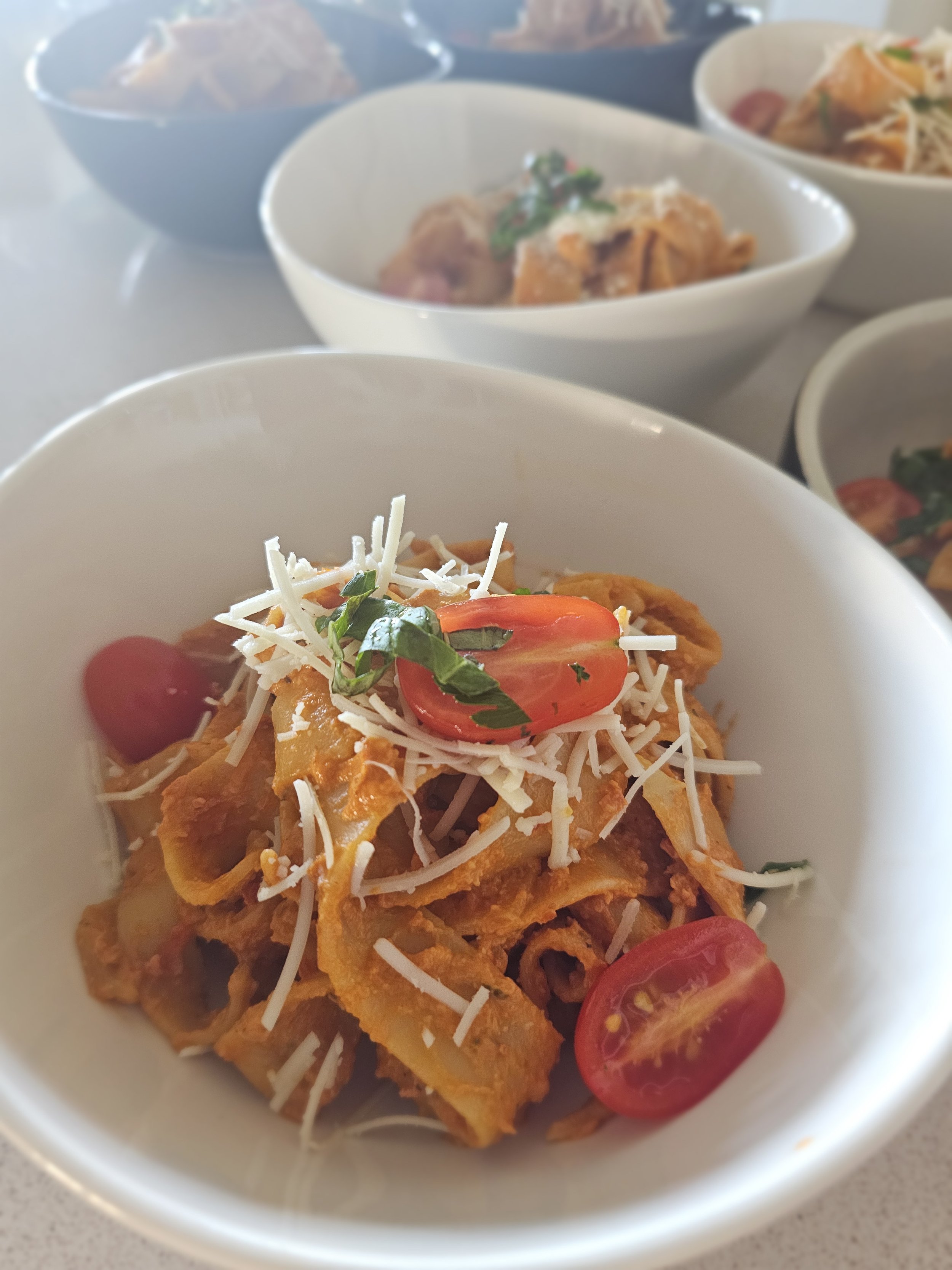Close-up of a bowl of tagliatelle pasta with pomodoro sauce parmesan and fresh cherry tomatoes