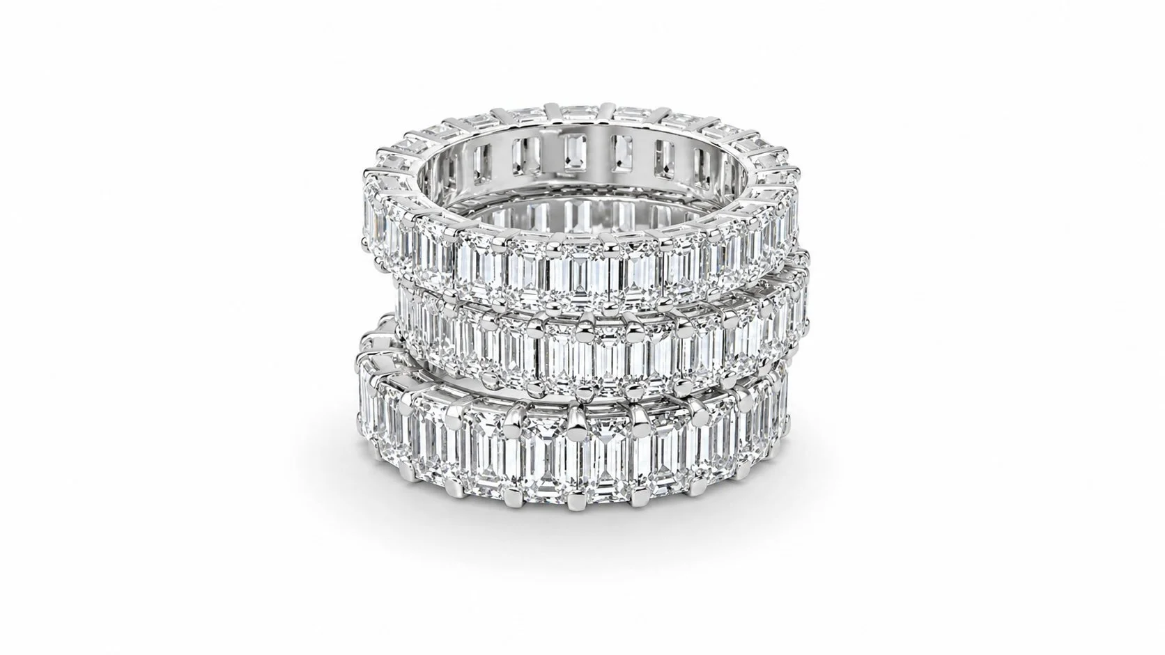 Three luxurious diamond-encrusted rings stacked on top of each other, featuring rectangular cut diamonds in a platinum setting.