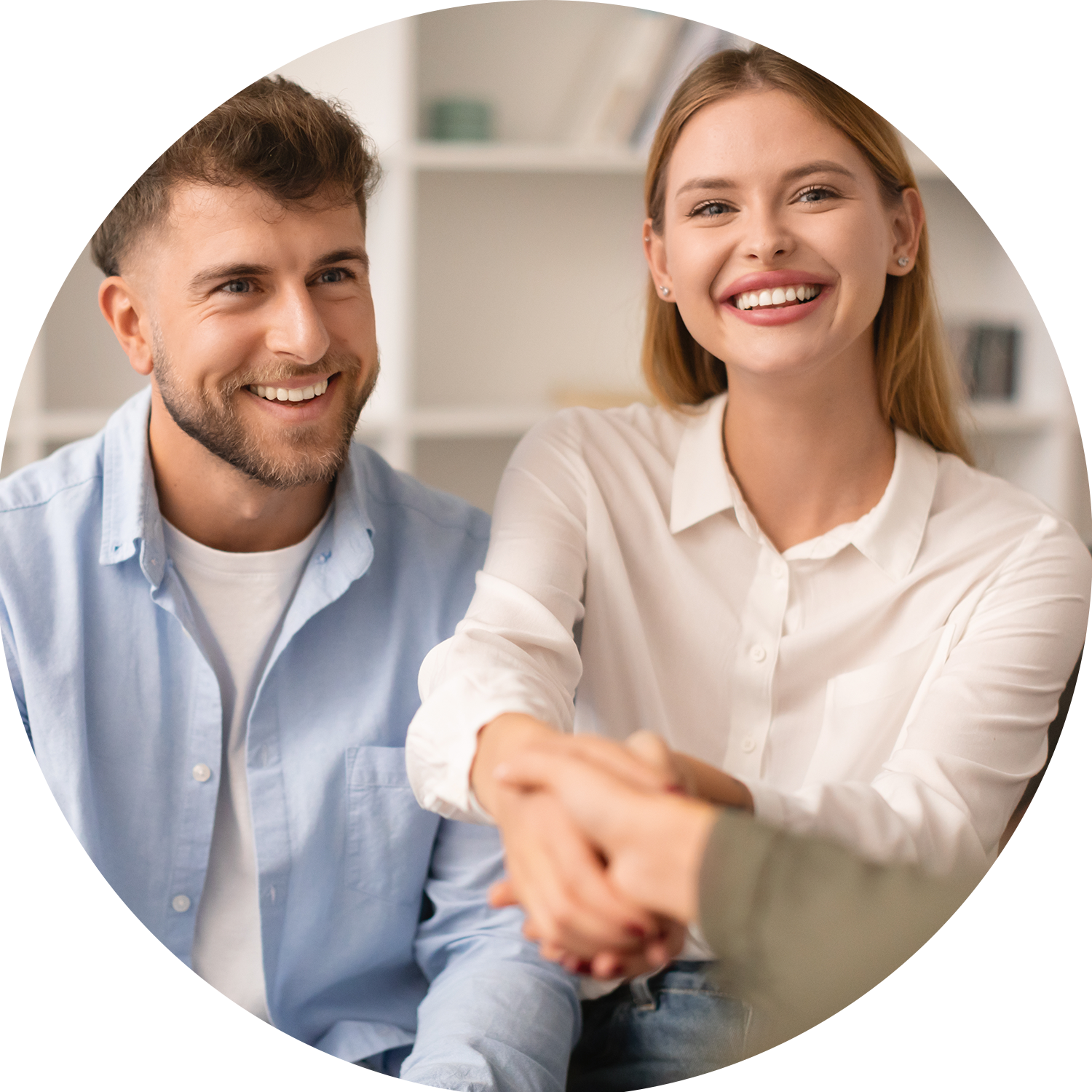 A man and woman smiling and shaking hands indoors.