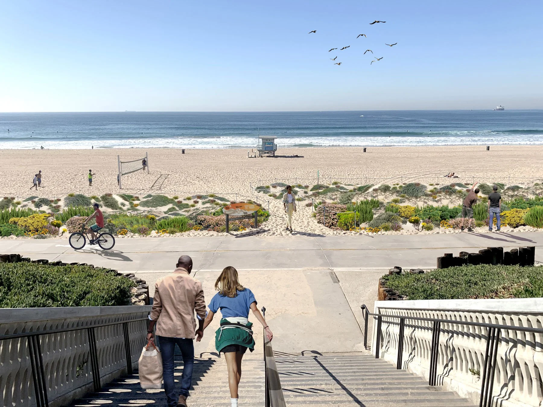 People walking down a set of stairs towards a beach with sand, a lifeguard tower, and ocean waves. The sky is clear and blue, with birds flying overhead. A cyclist is riding along the sidewalk near the stairs.