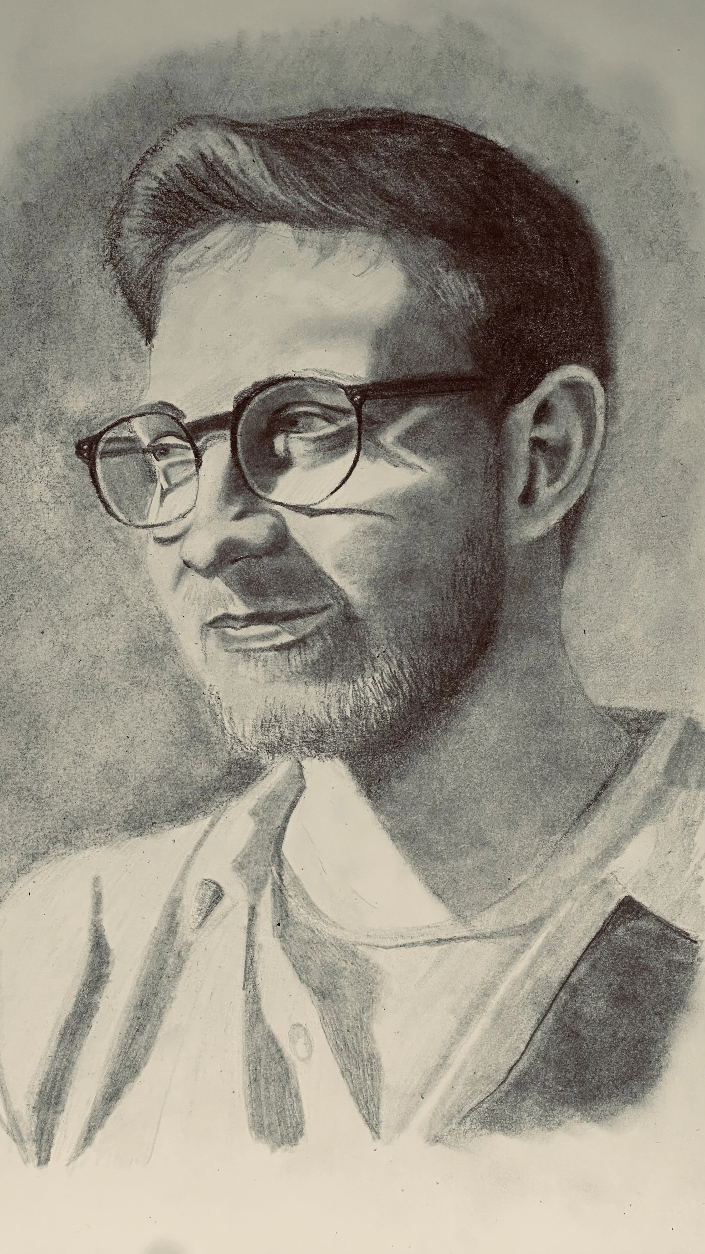 A black and white pencil sketch of a man wearing round glasses, with a beard and mustache, and short, styled hair, dressed in a shirt.