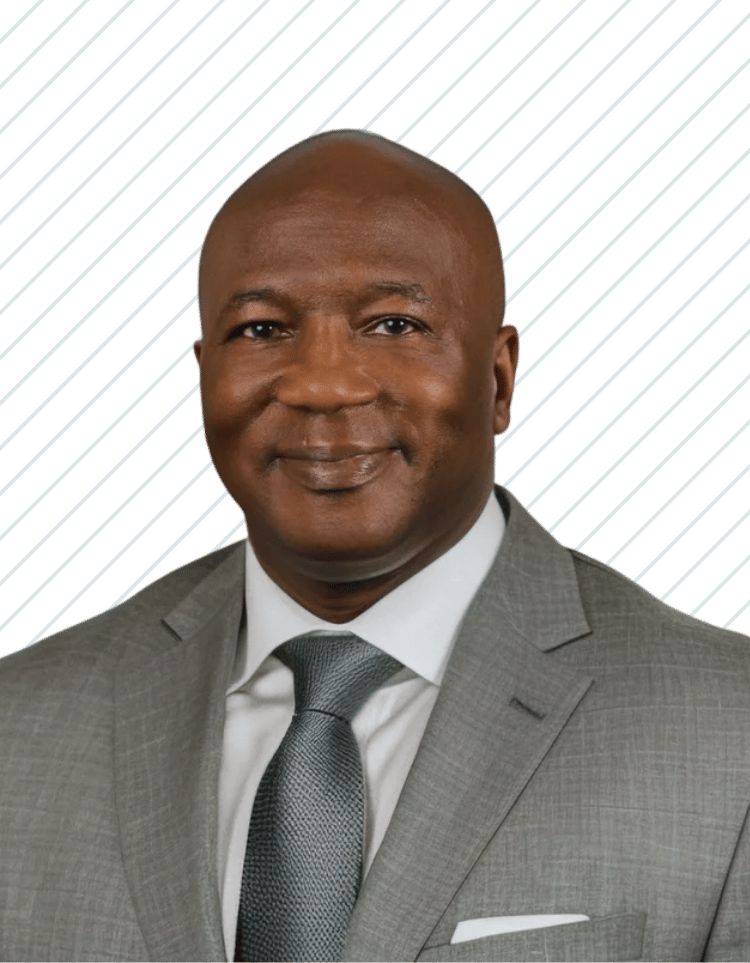 A smiling African American man wearing a gray suit, white shirt, and gray tie, with a patterned pocket square, Dr. Michael Railey of Bay Wellness Group.