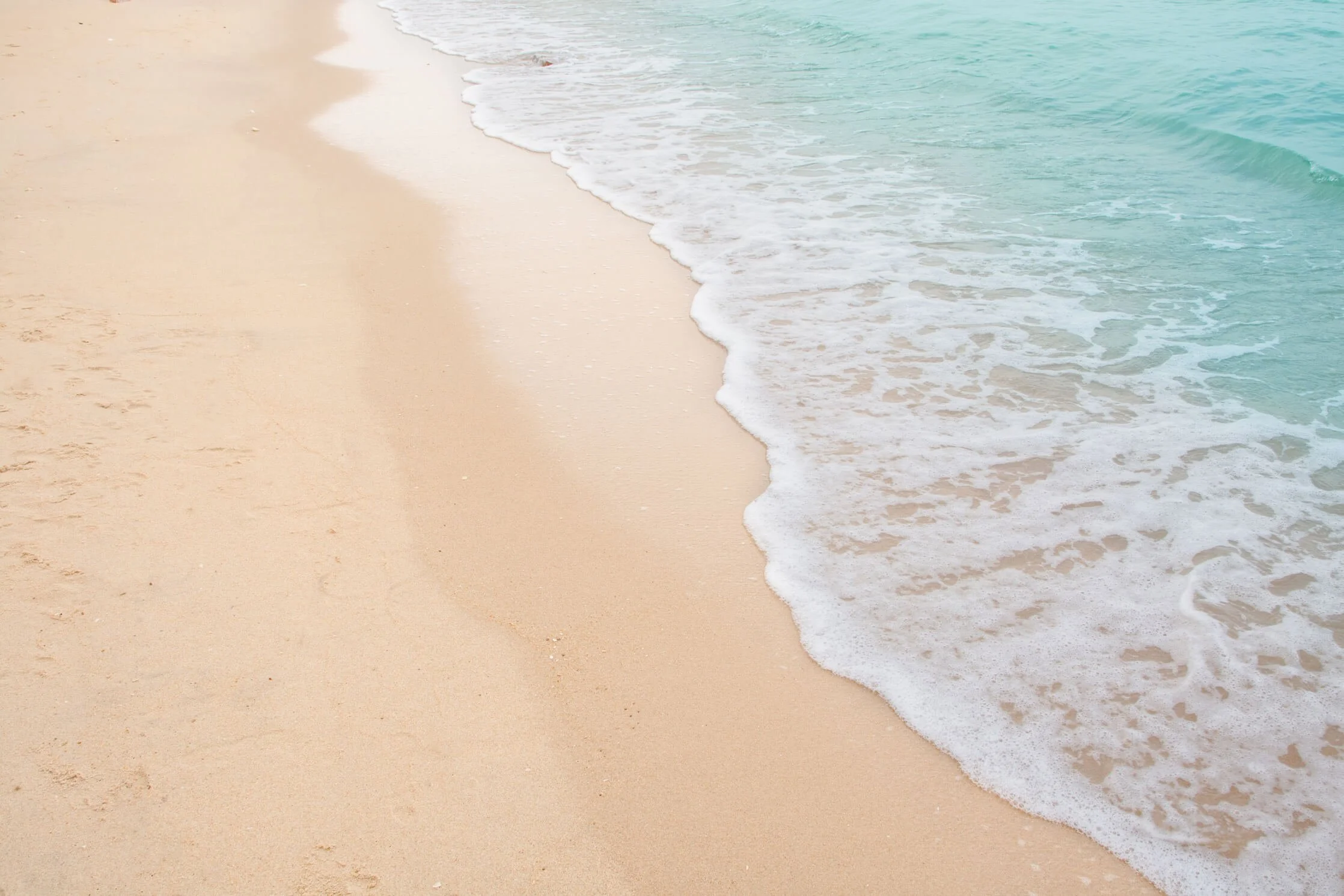Empty sandy beach with gentle waves washing onto the shore, Panama City Beach, Florida shoreline.