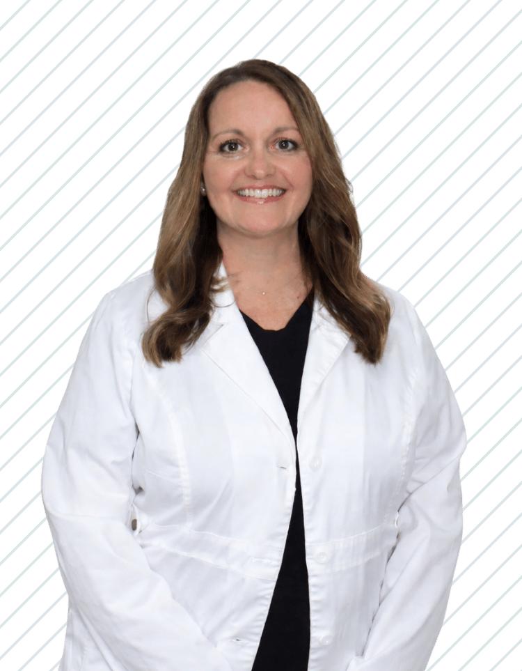 A woman with long brown hair smiling, wearing a white coat, Amanda Worthington of Bay Wellness Group.