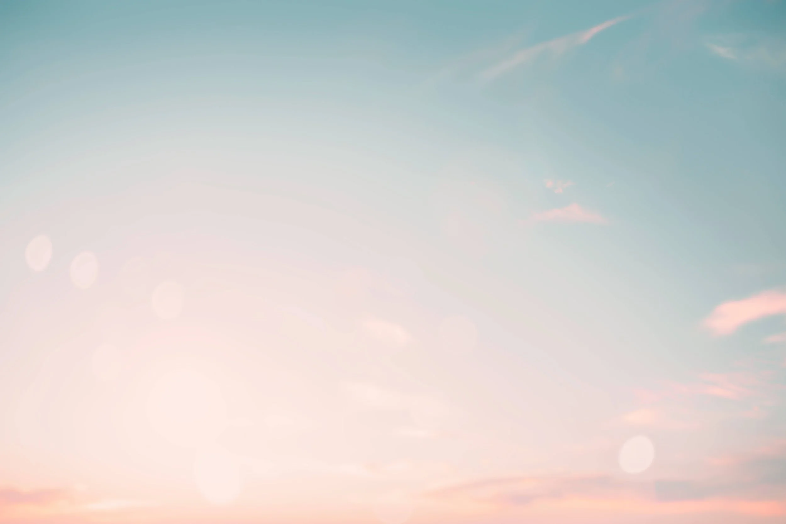 A sky with a gradient of light blue and soft pink hues, with a few faint clouds and lens flares.