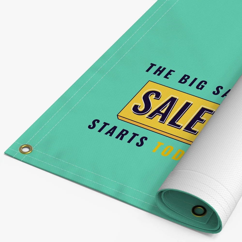Close-up image of a teal-colored sale sign or banner with text that reads 'The big sale starts today' and a corner rolled back to reveal a white back side.