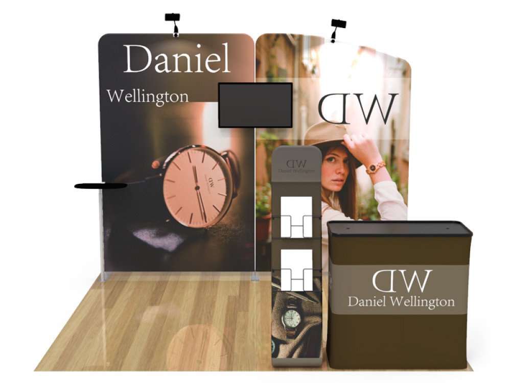 Trade show booth for Daniel Wellington featuring a large watch image, a woman wearing a watch, and branding with the initials DW and full brand name.