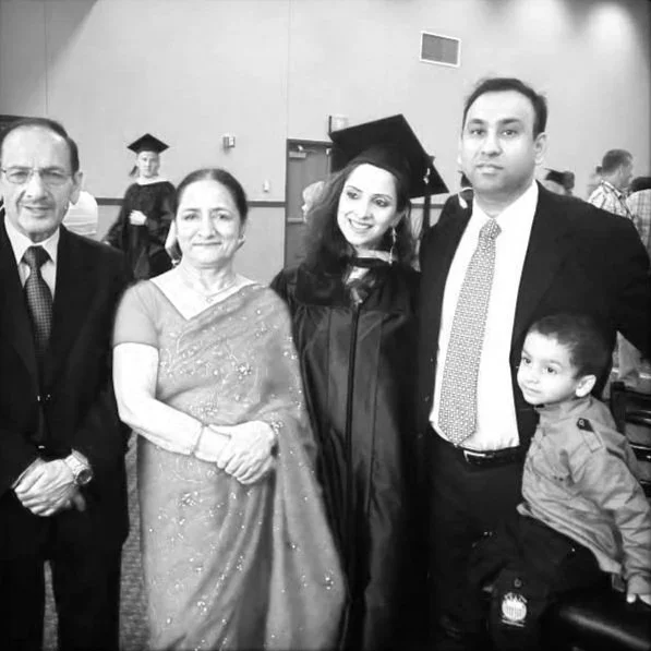 Group of five people, including a graduate in cap and gown, celebrating at graduation ceremony.