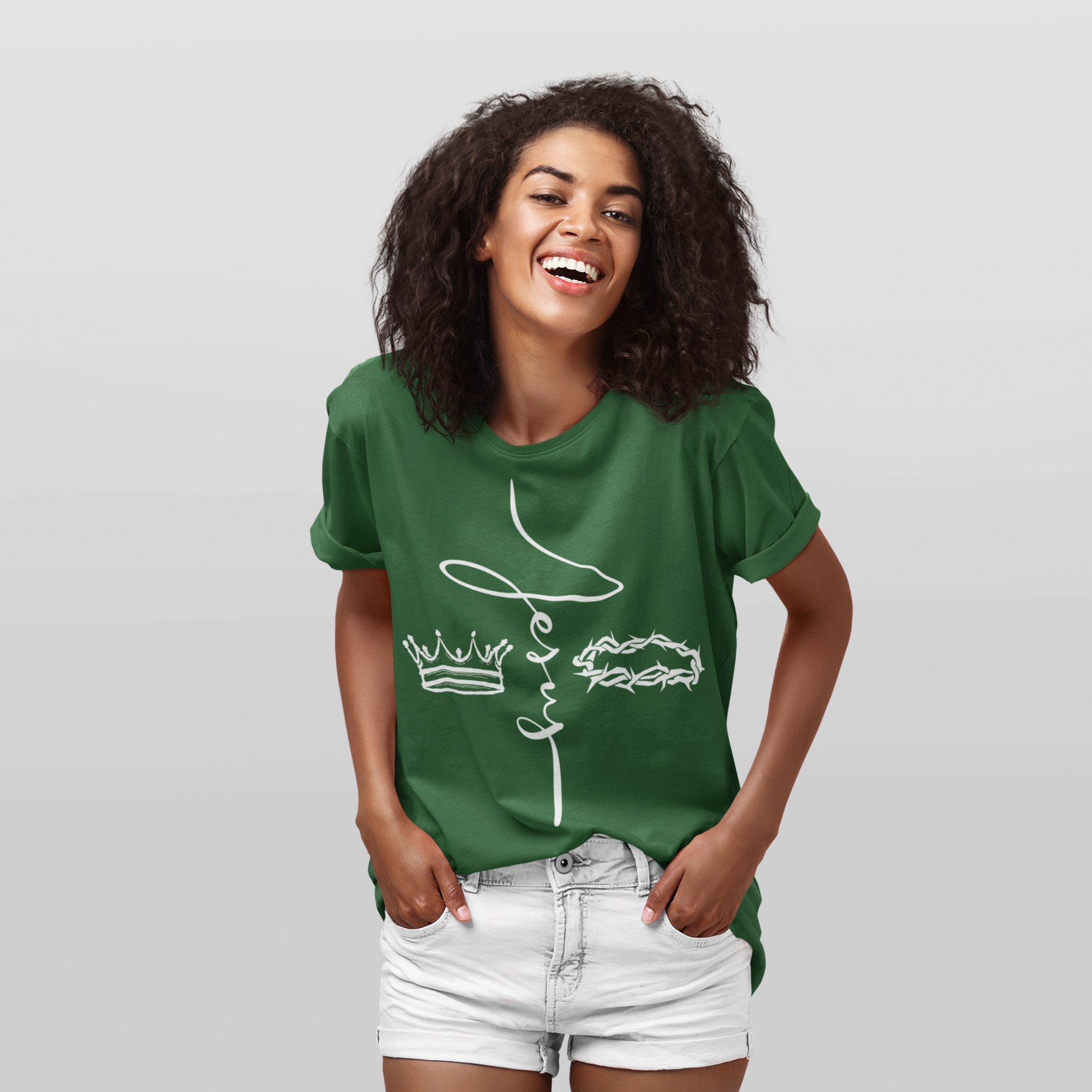 Young woman with curly dark hair wearing a green t-shirt and white denim shorts, smiling against a plain background.
