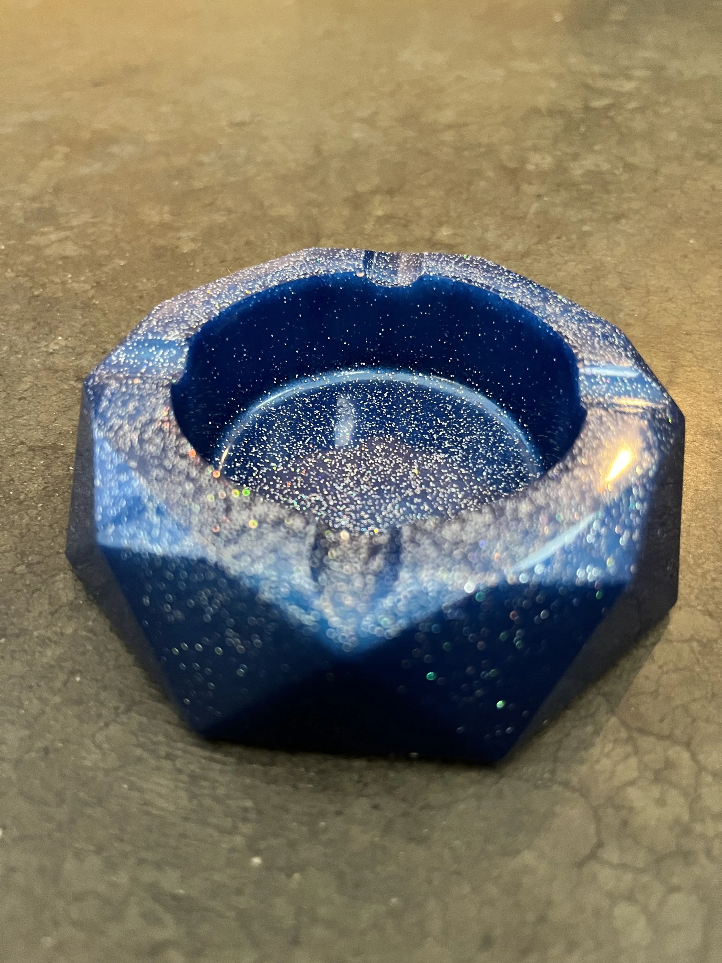 Close-up of a handmade blue, glittery, geometric-shaped ashtray/bowl.