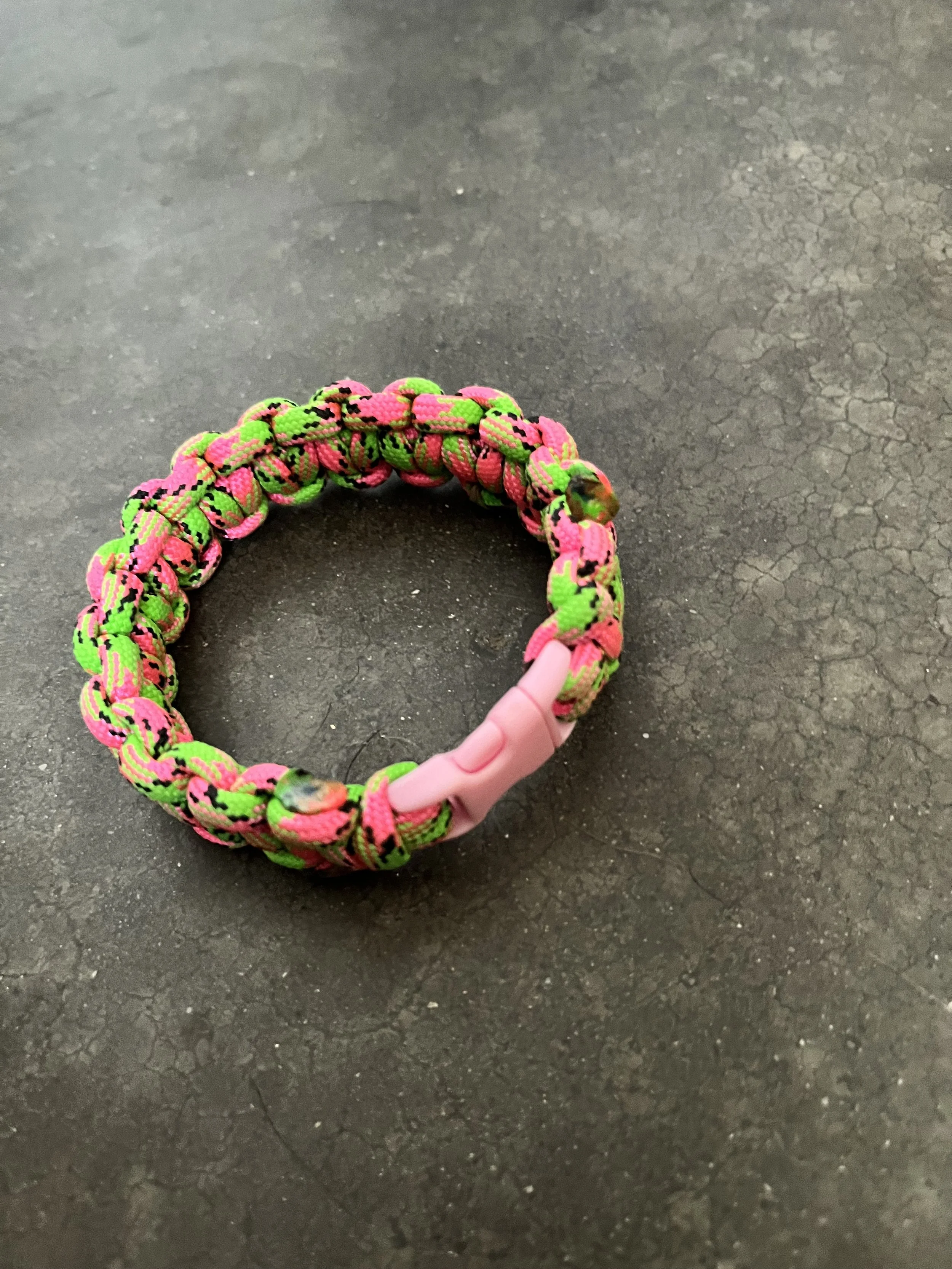 A handmade pink and geen paracord bracelet.