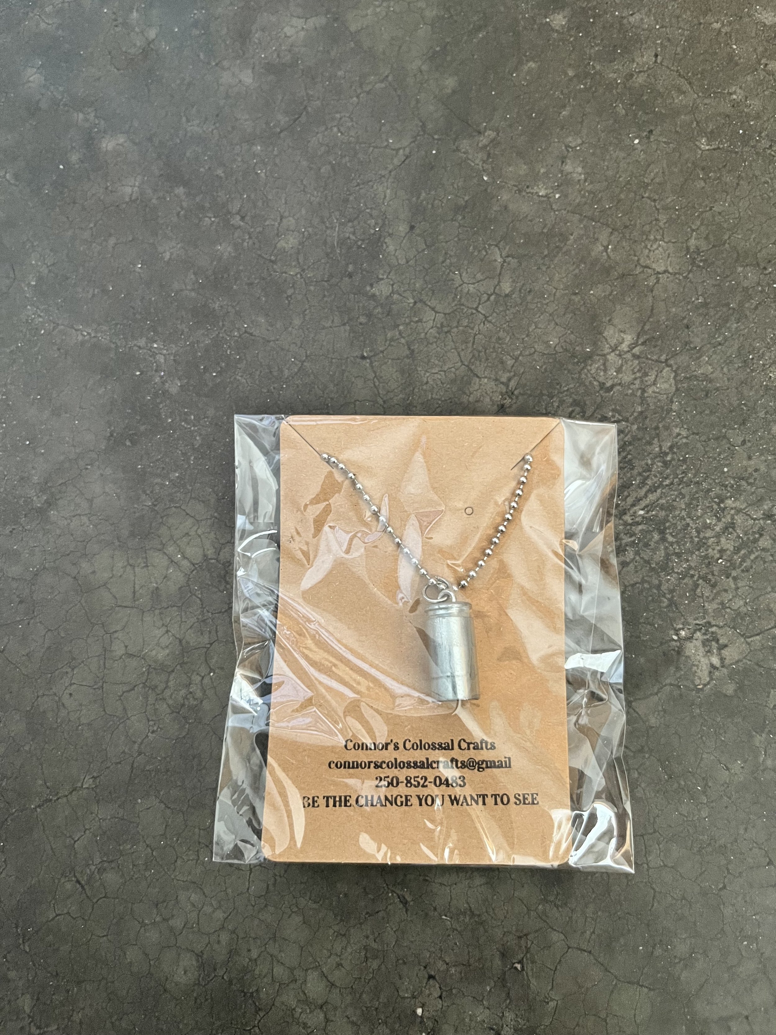 A handmade 9mm gun casing necklace wrapped in plastic.