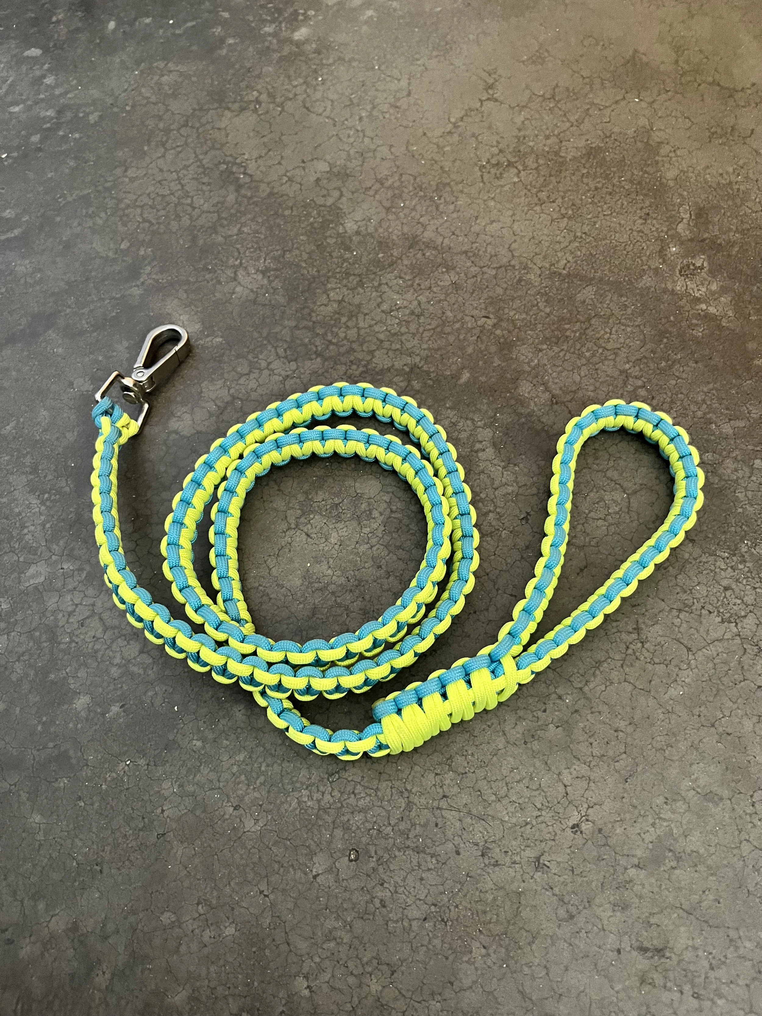 Colorful paracord lanyard with metal clasp on a cracked dark surface.