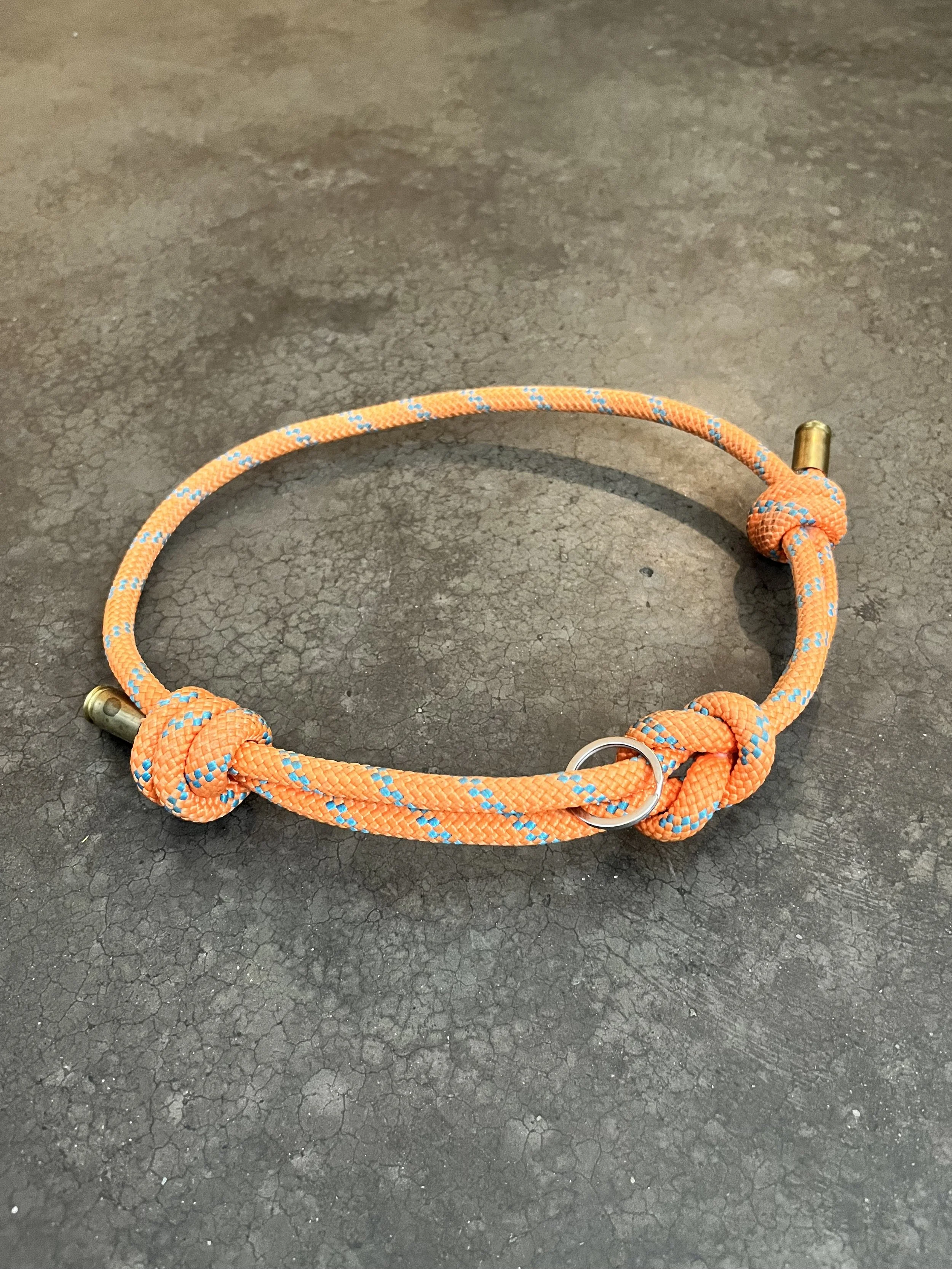 Orange handmade dog collar made from rope and gun casings.