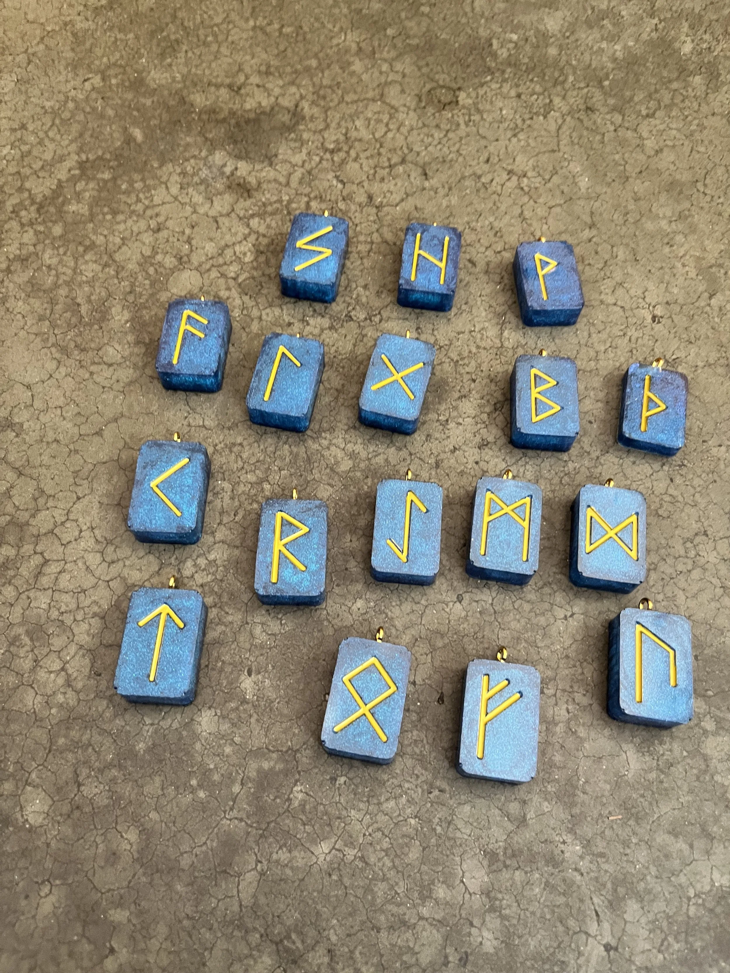 Blue rune stones with yellow runic symbols arranged on a cracked brown surface.