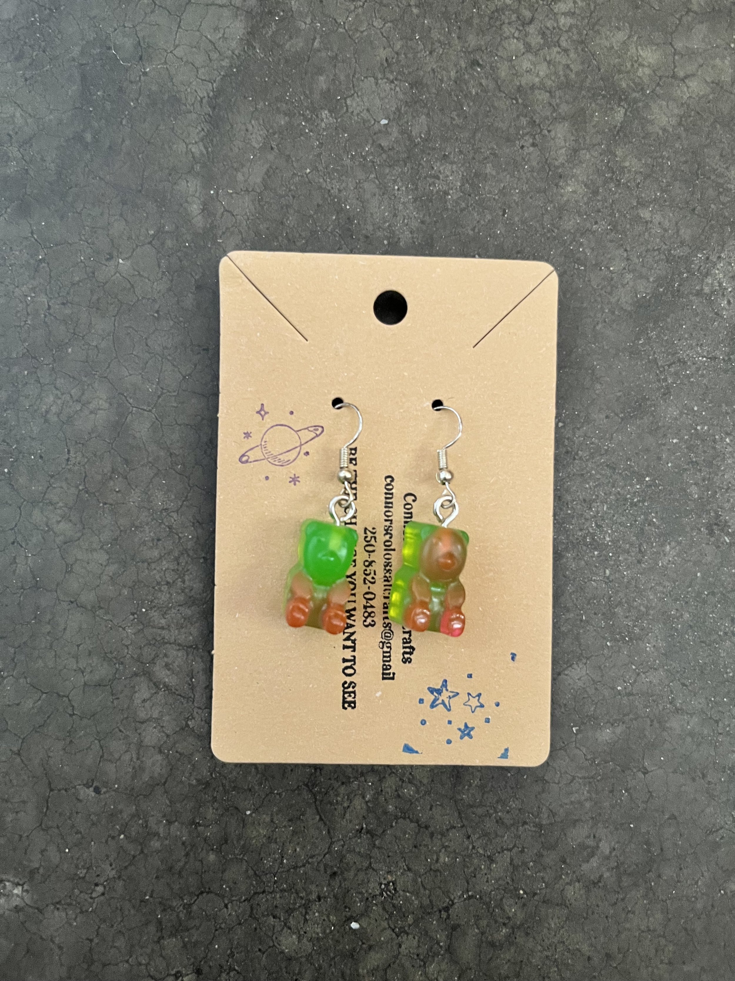 Colorful handmade gummy bear earrings on a cardboard display card.