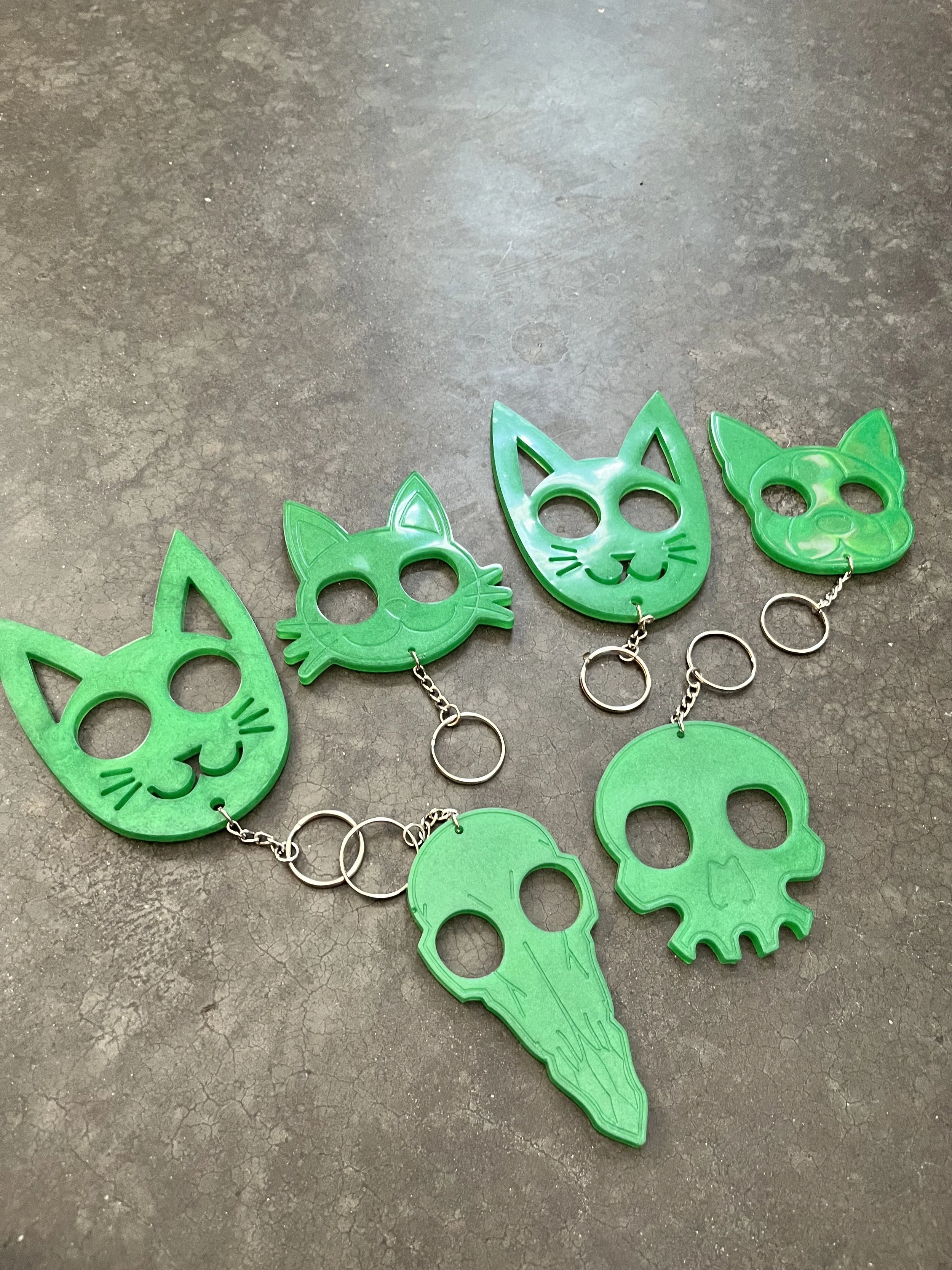 Green resin epoxy emergency keychains on a rough dark surface.