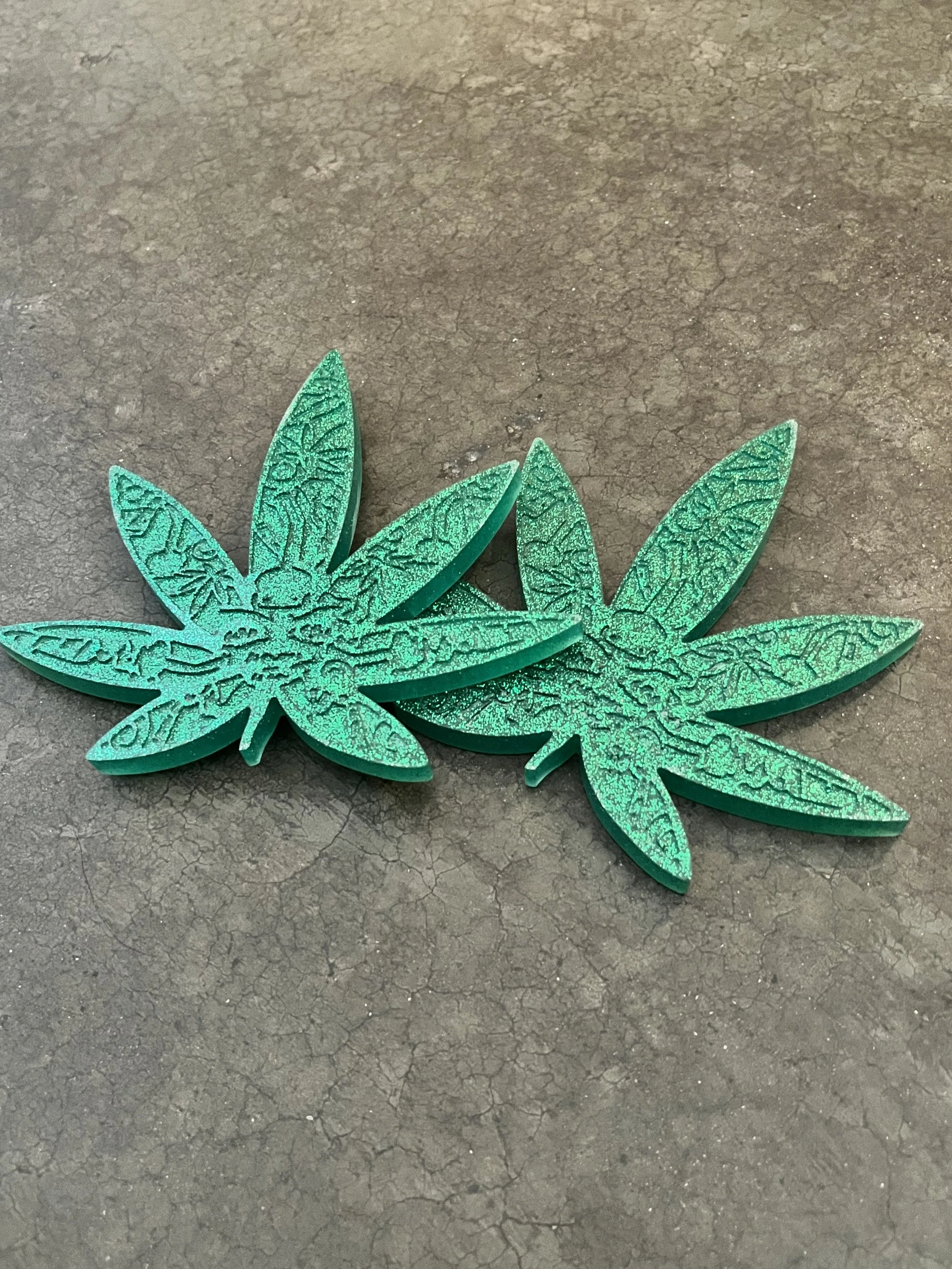 Close-up of handmade green glittery epoxy resin marijuana coasters.