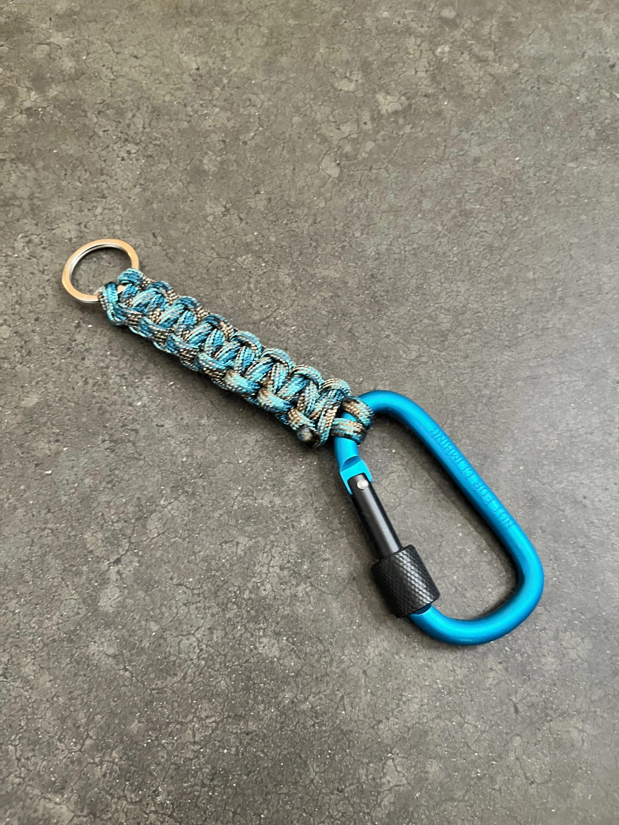 A handmade blue paracord lanyard attached to a blue carabiner.