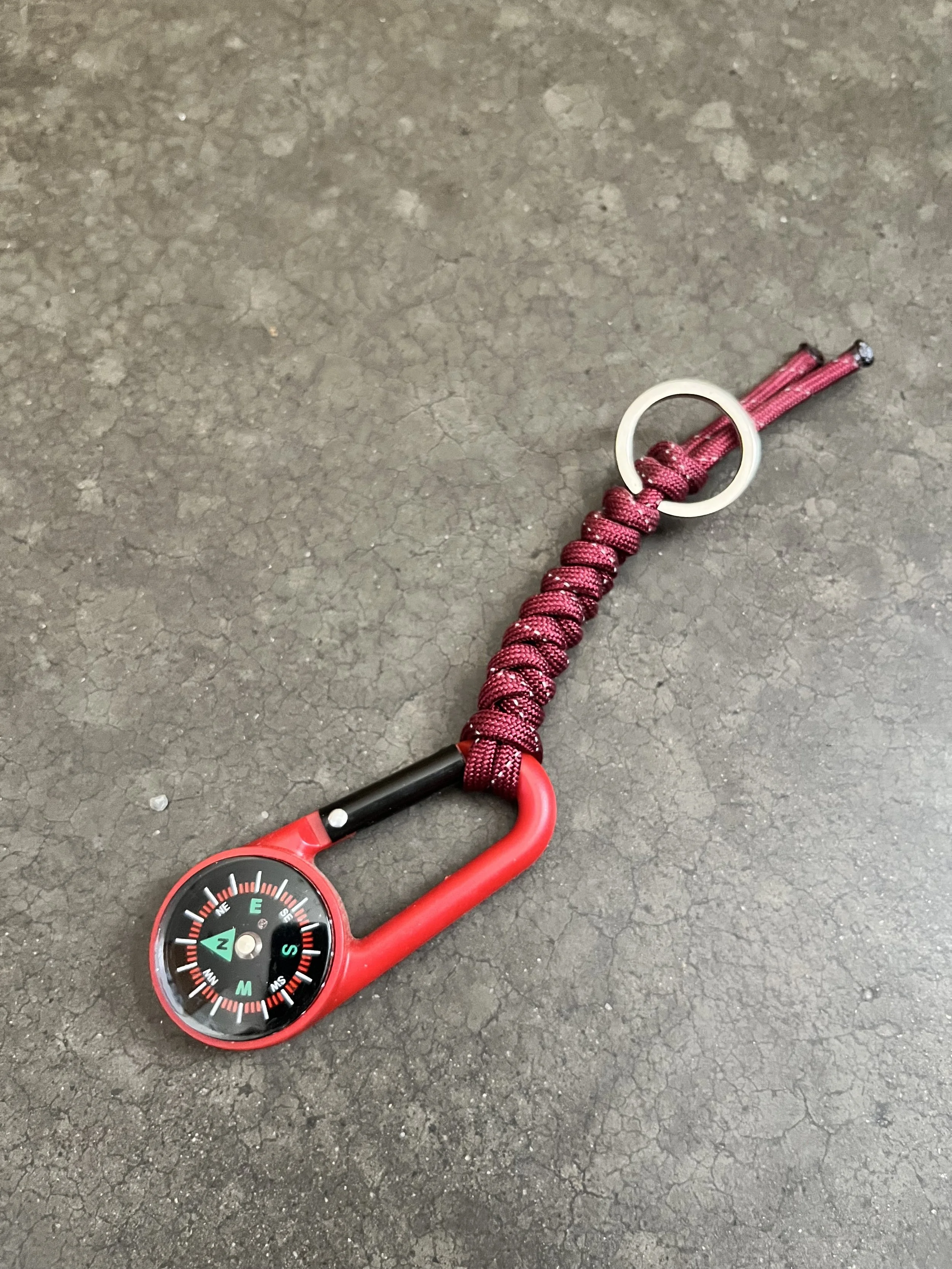 A red compass attached to braided paracord.